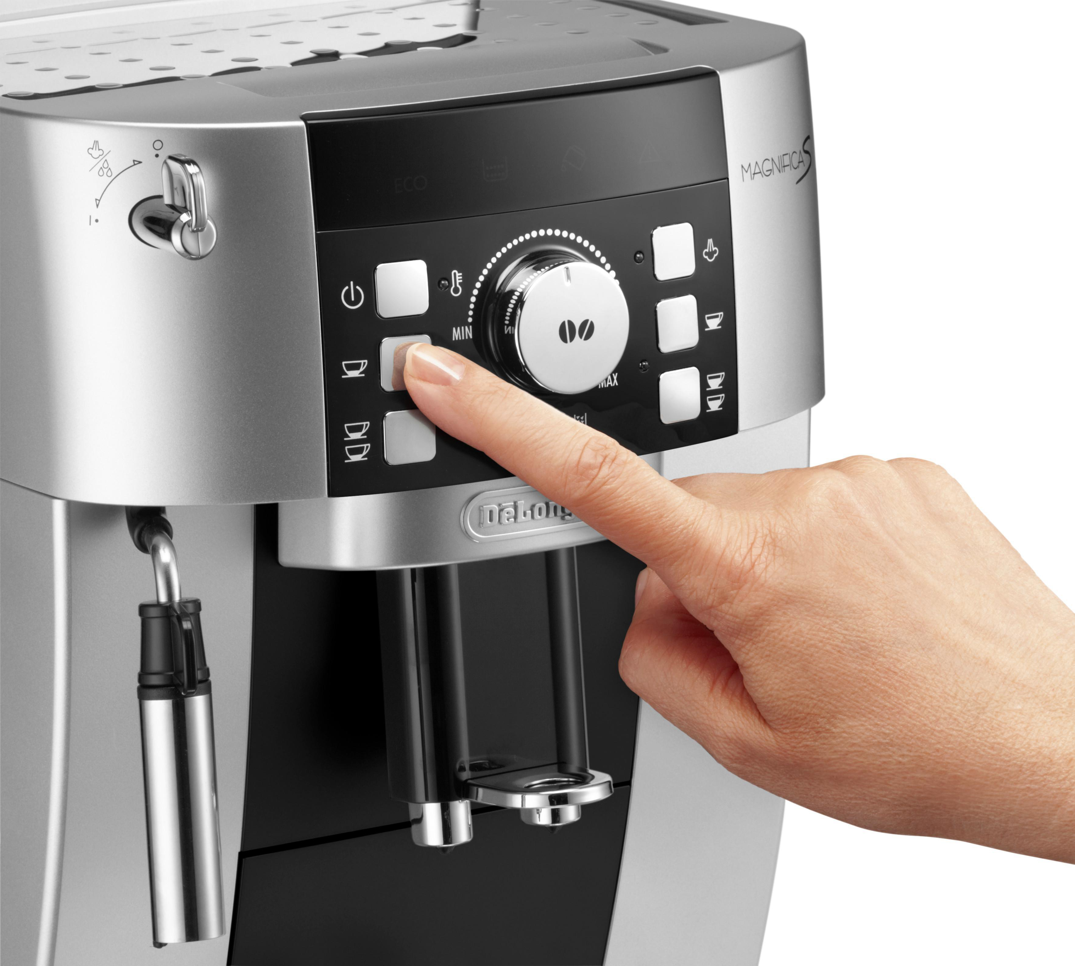 Die Hand einer Person drückt eine Taste an einer silber-schwarzen Kaffeemaschine. Weißer Hintergrund.