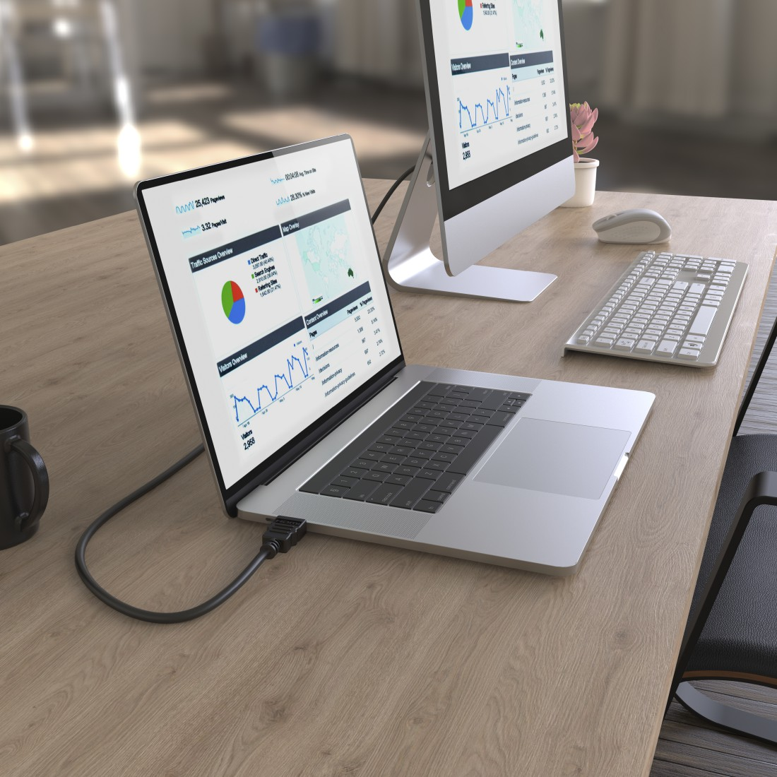 Laptop und Monitor auf Holzschreibtisch mit Grafiken. Tastatur und Maus vorhanden.