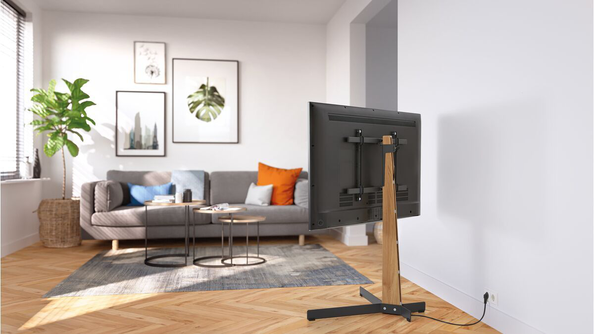 Salon avec TV sur un support en bois. Canapé, art et fenêtre en arrière-plan.