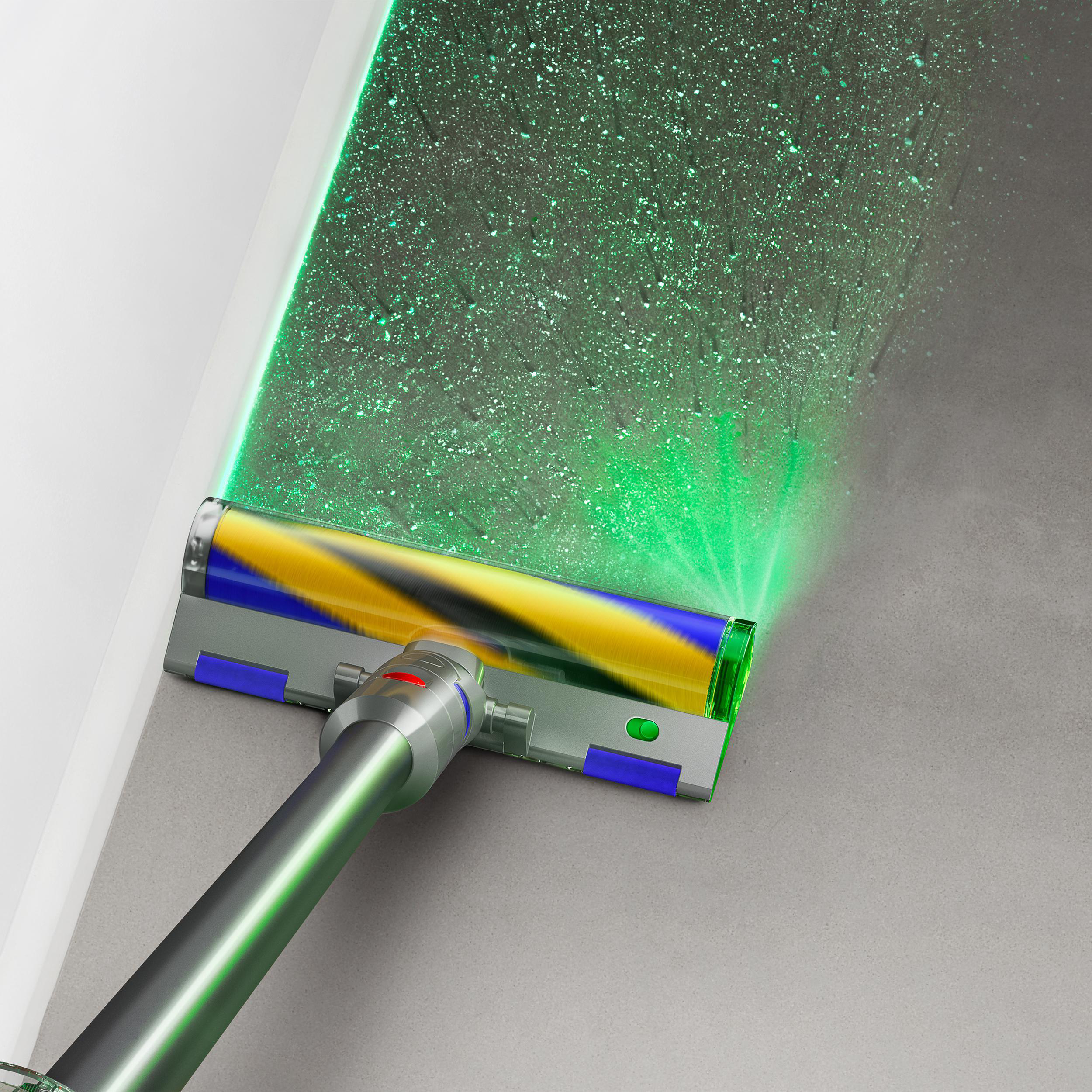 Staubsaugerkopf mit grünem Licht auf grauem Boden. Staubpartikel werden hervorgehoben. Weiße Wand links.