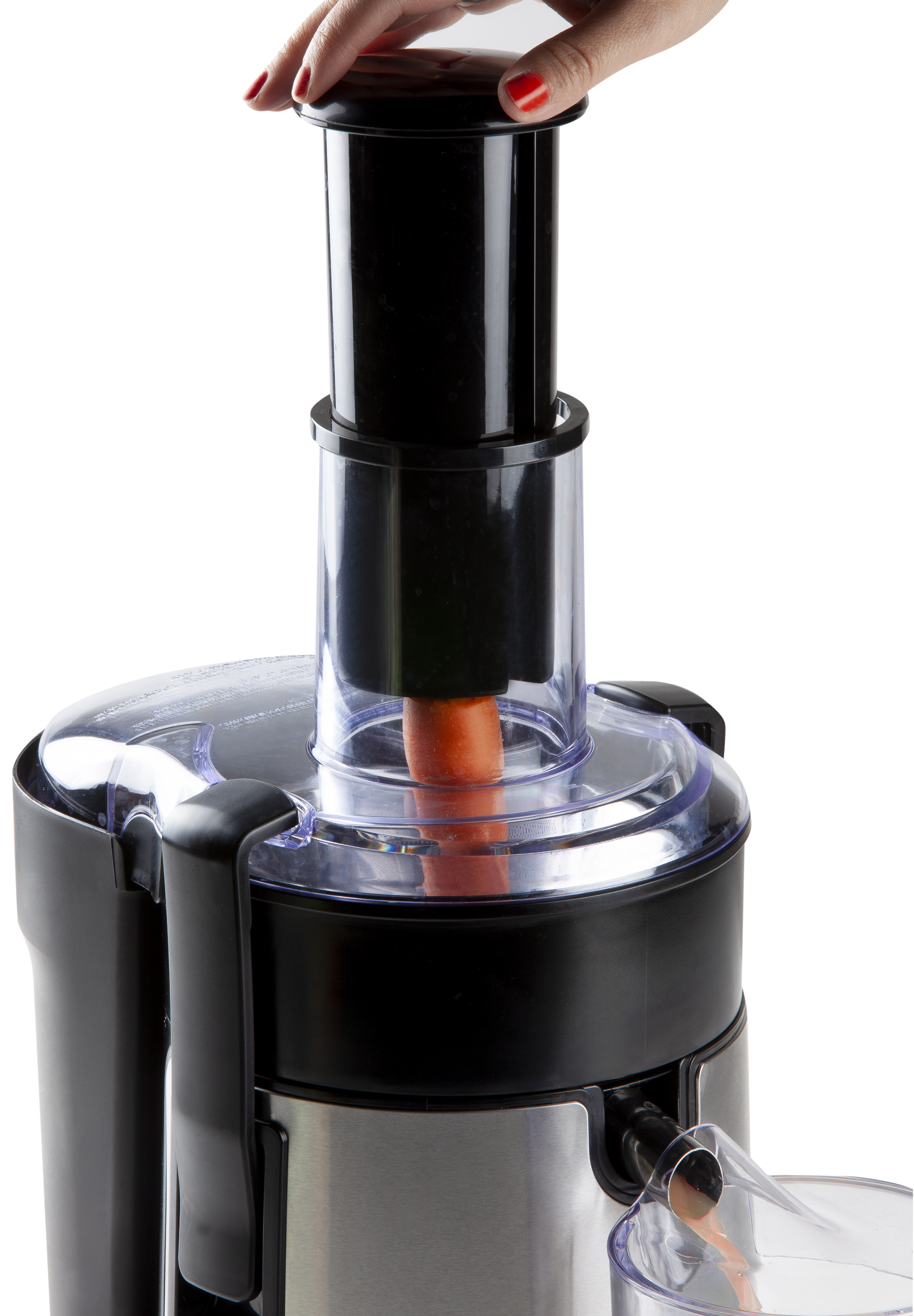 A person's hand adding a carrot to a black and stainless steel juicer.