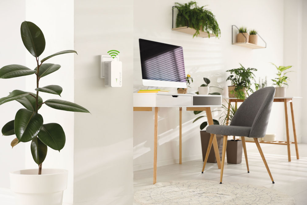 Een wit apparaat dat in een muur is gestoken, met een bureau en planten op de achtergrond.