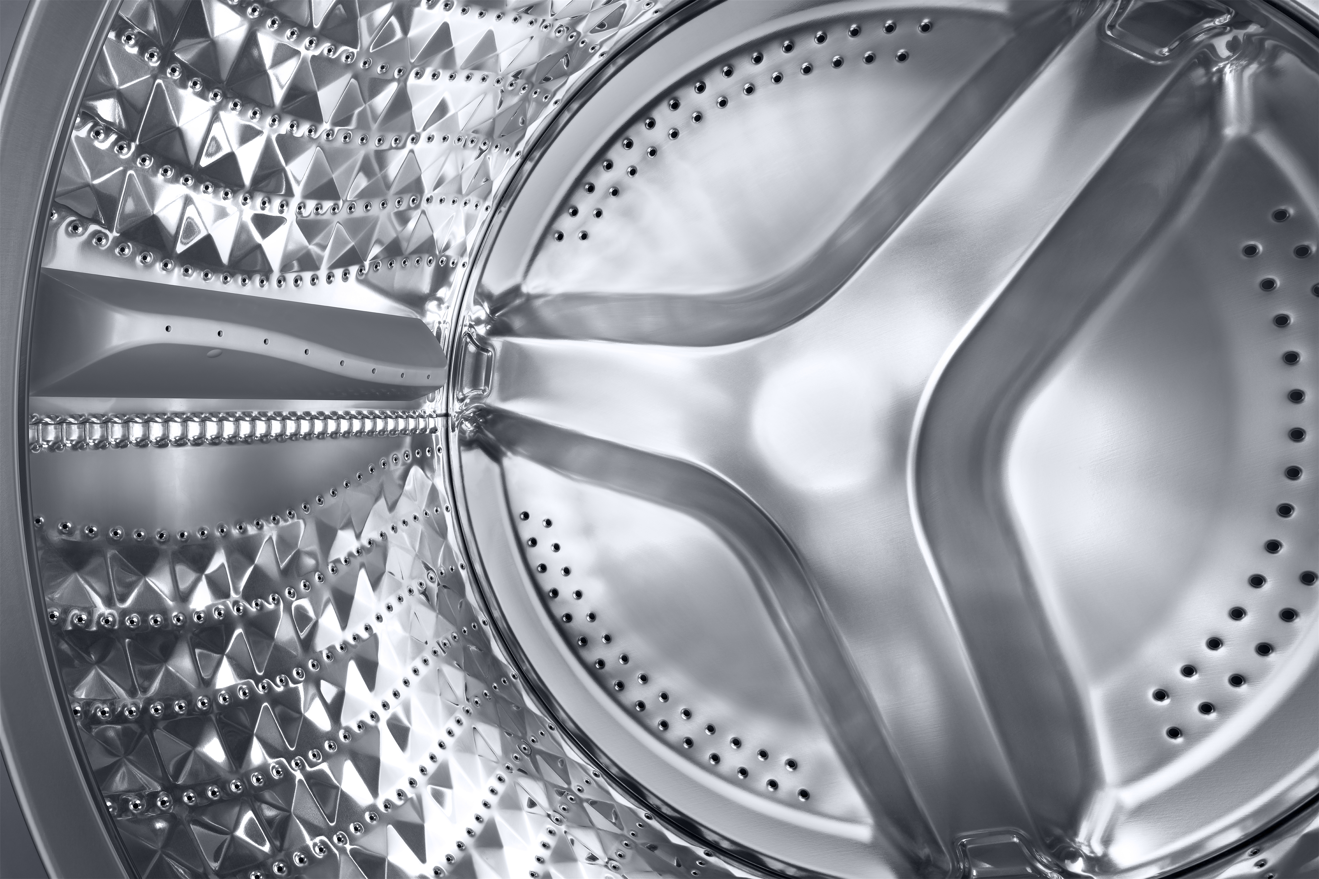 Nahaufnahme des Inneren einer Waschmaschinentrommel. Metalloberfläche mit Perforationen und zentralen Elementen.