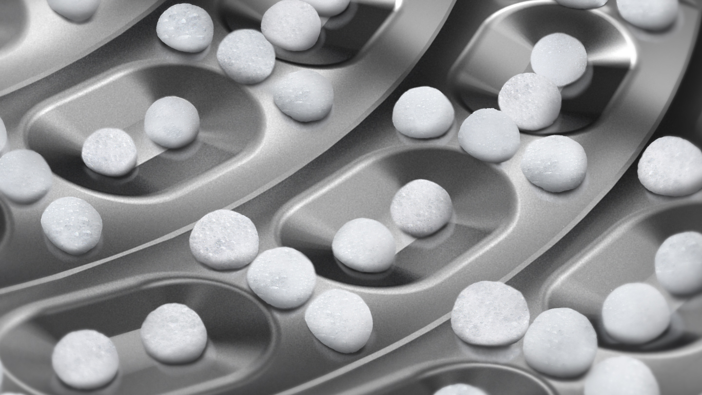 Nahaufnahme des Inneren einer Waschmaschinentrommel mit vielen weißen Pellets.