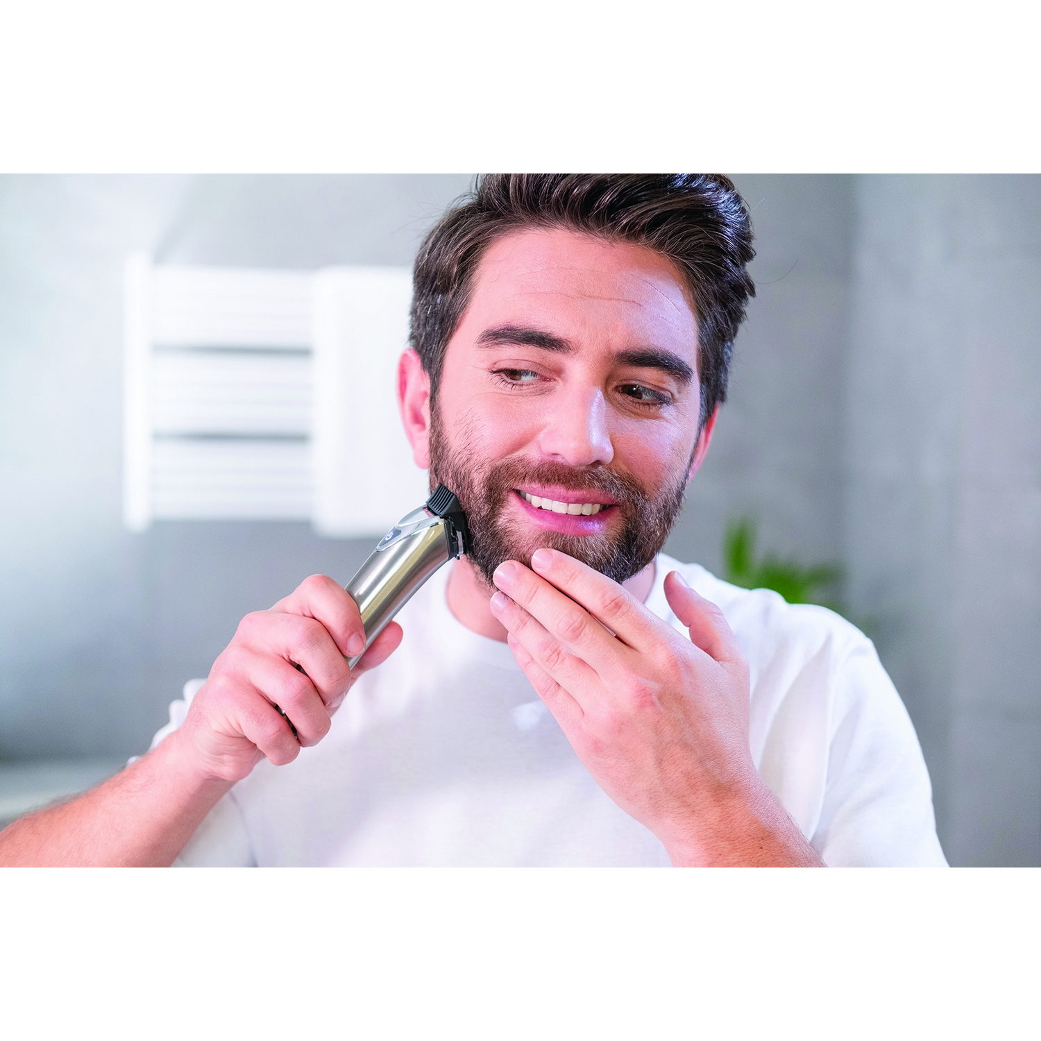 Un hombre se afeita la barba con una recortadora eléctrica en un baño.