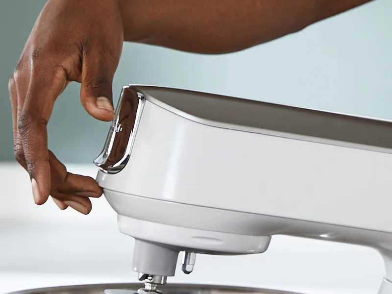 A hand is shown pressing a button on a mixer.