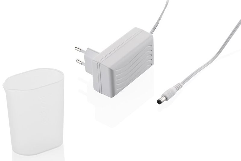Fehér hálózati adapter, kis műanyag pohár és kábel fehér felületen.