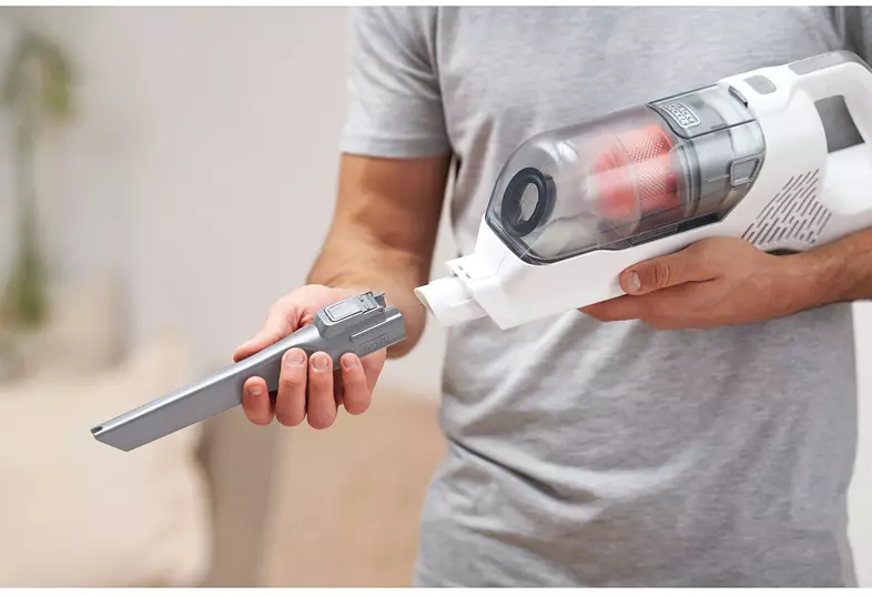 Une personne tenant un aspirateur à main blanc et gris avec une fixation.