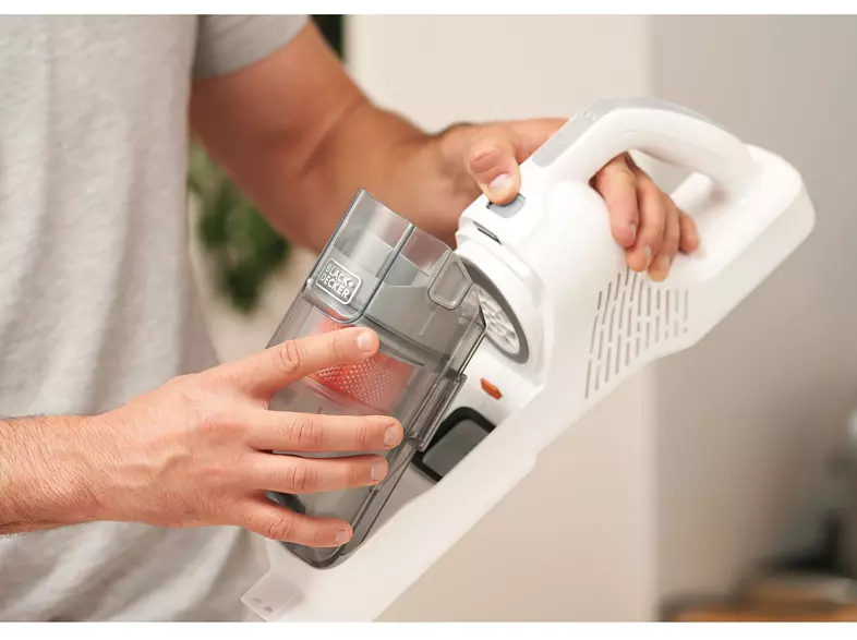 Une personne retire un récipient d'un aspirateur à main blanc et gris.