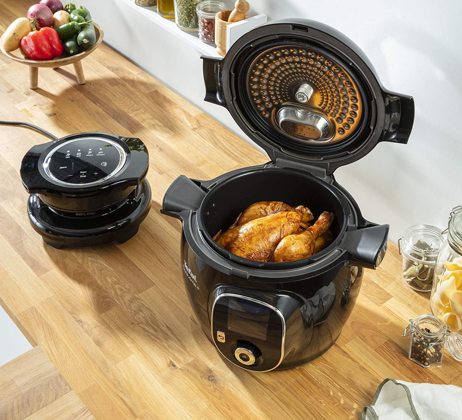 Black pressure cooker with chicken inside, open lid, on a wooden surface.