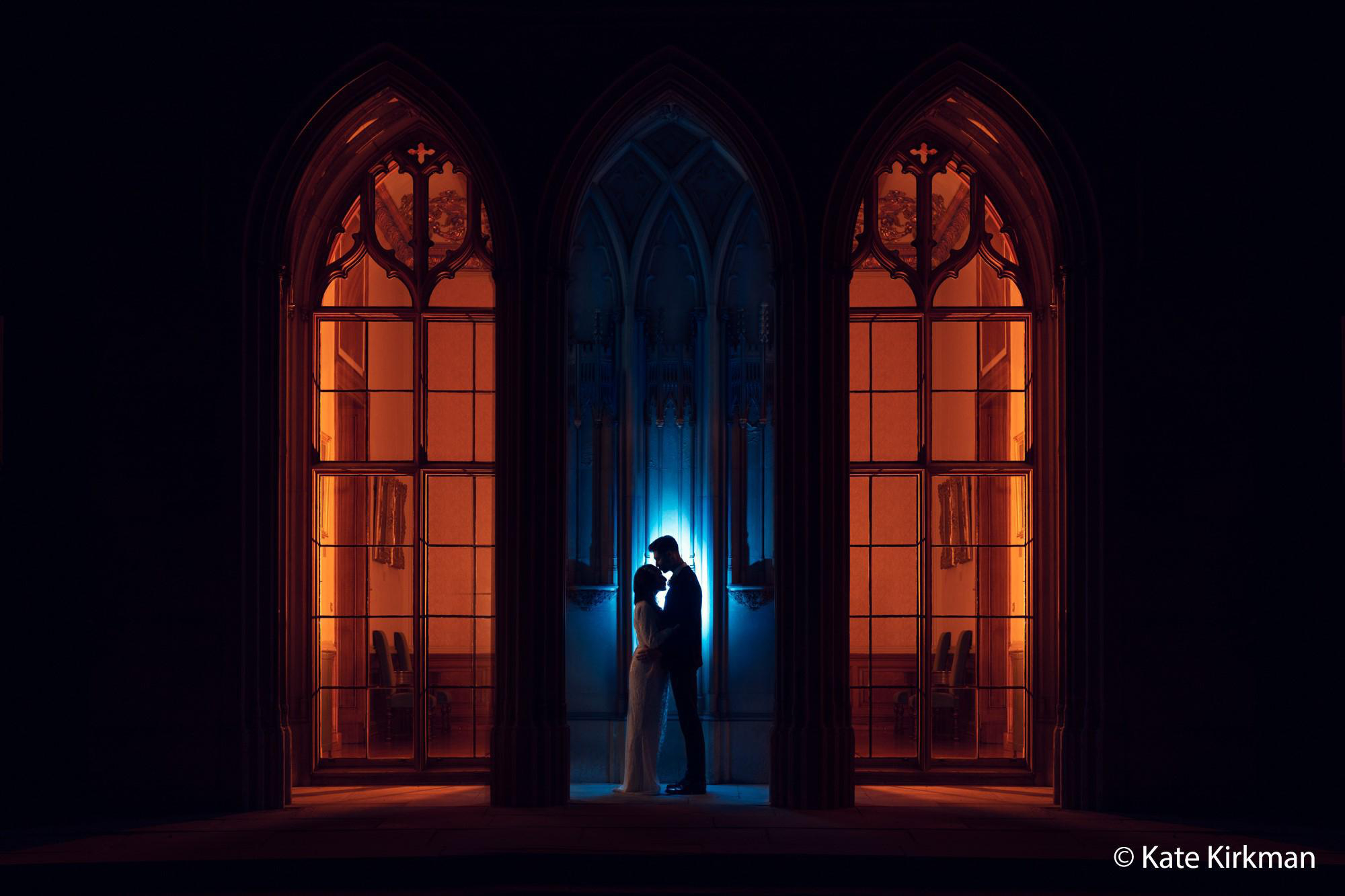 Paar umarmt sich im Schatten in einer Kirche. Licht von Fenstern erzeugt eine dramatische Kulisse.