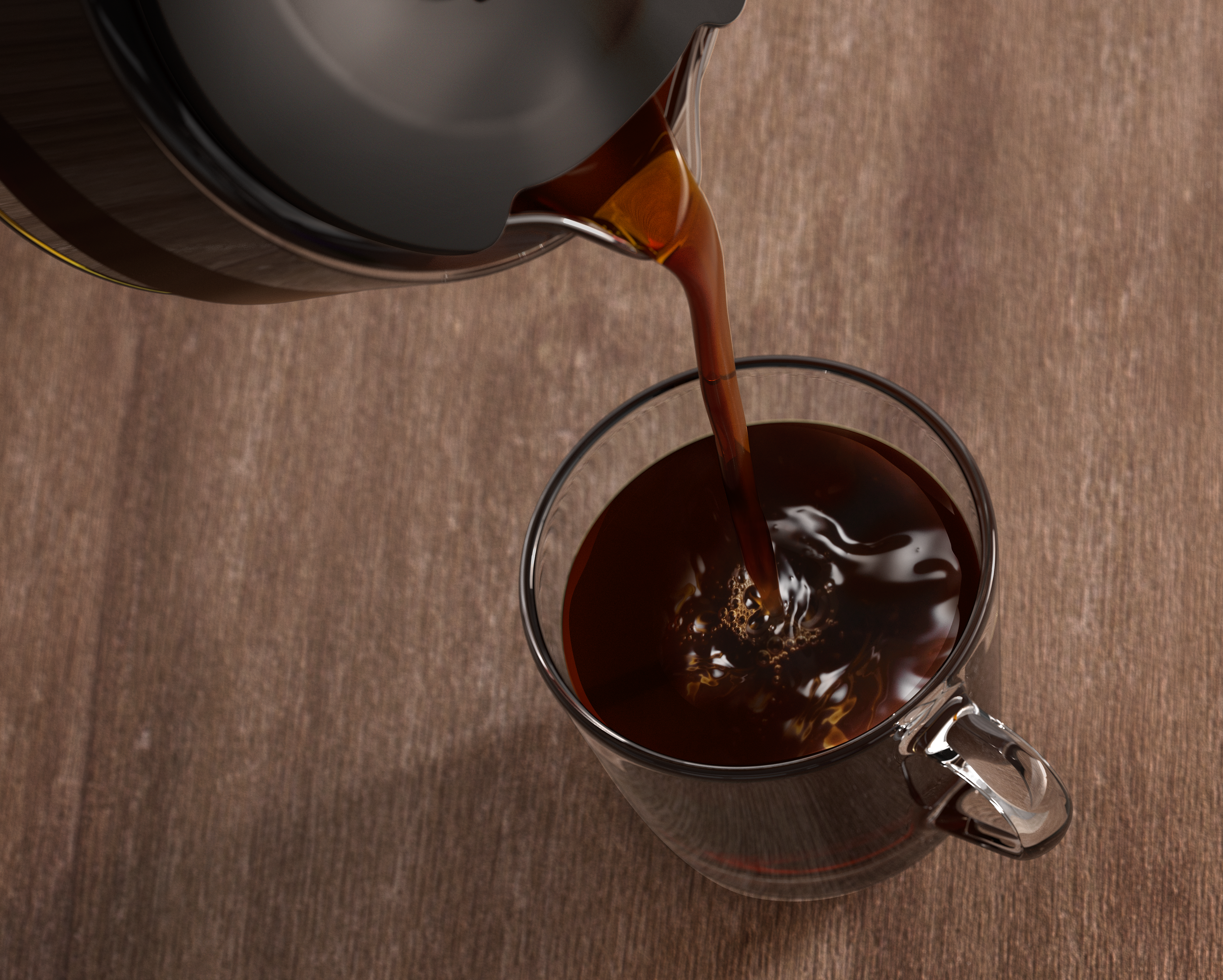 Kaffee gießt aus einer schwarzen Karaffe in eine klare Glas-Tasse auf einem Holztisch.