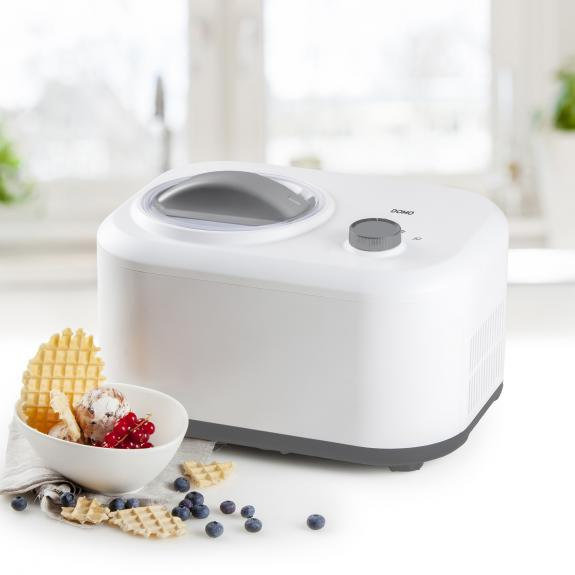 Witte ijsmachine met een kom ijs, bessen en wafels ervoor.
