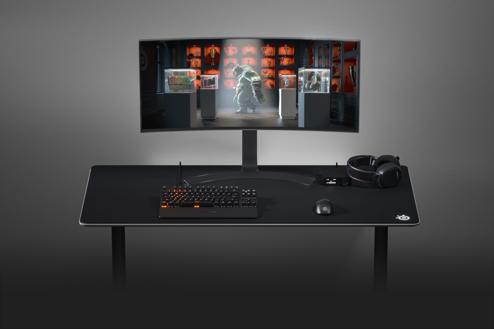 Gaming setup: monitor, toetsenbord, muis en headset. De monitor toont een game scène.