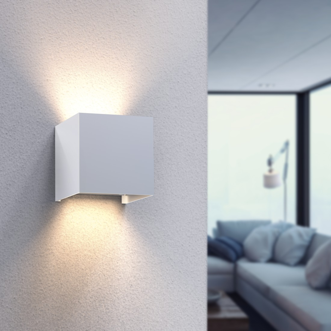 Eine weiße, an der Wand befestigte Würfelleuchte. Sie wirft Licht nach unten und auf die Wand.