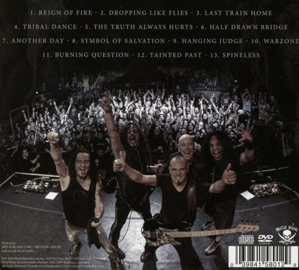 Eine Menschenmenge vor einer Bühne. Die Band steht auf der Bühne, mit Text auf der Rückseite.