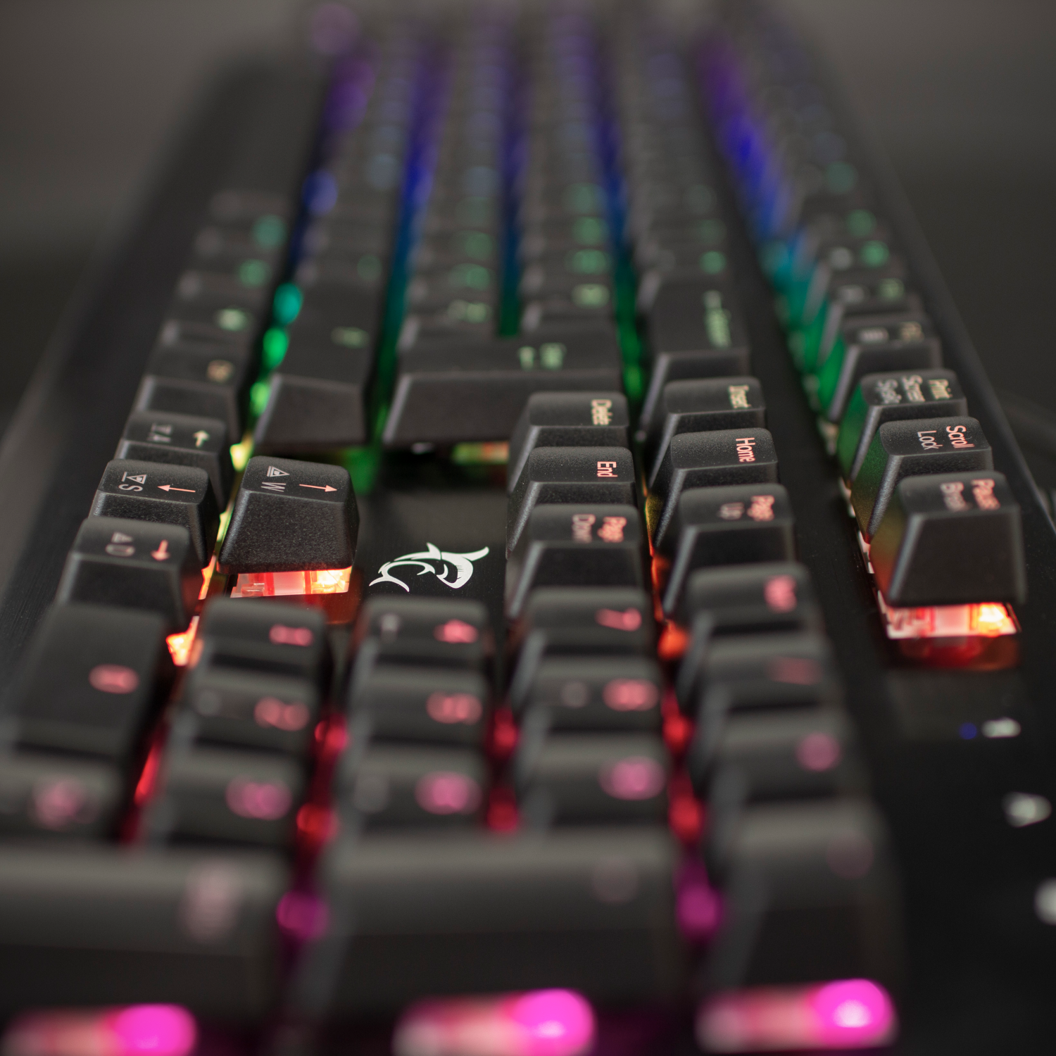 Egy háttérvilágítású gamer billentyűzet közeli képe színes billentyűkkel.