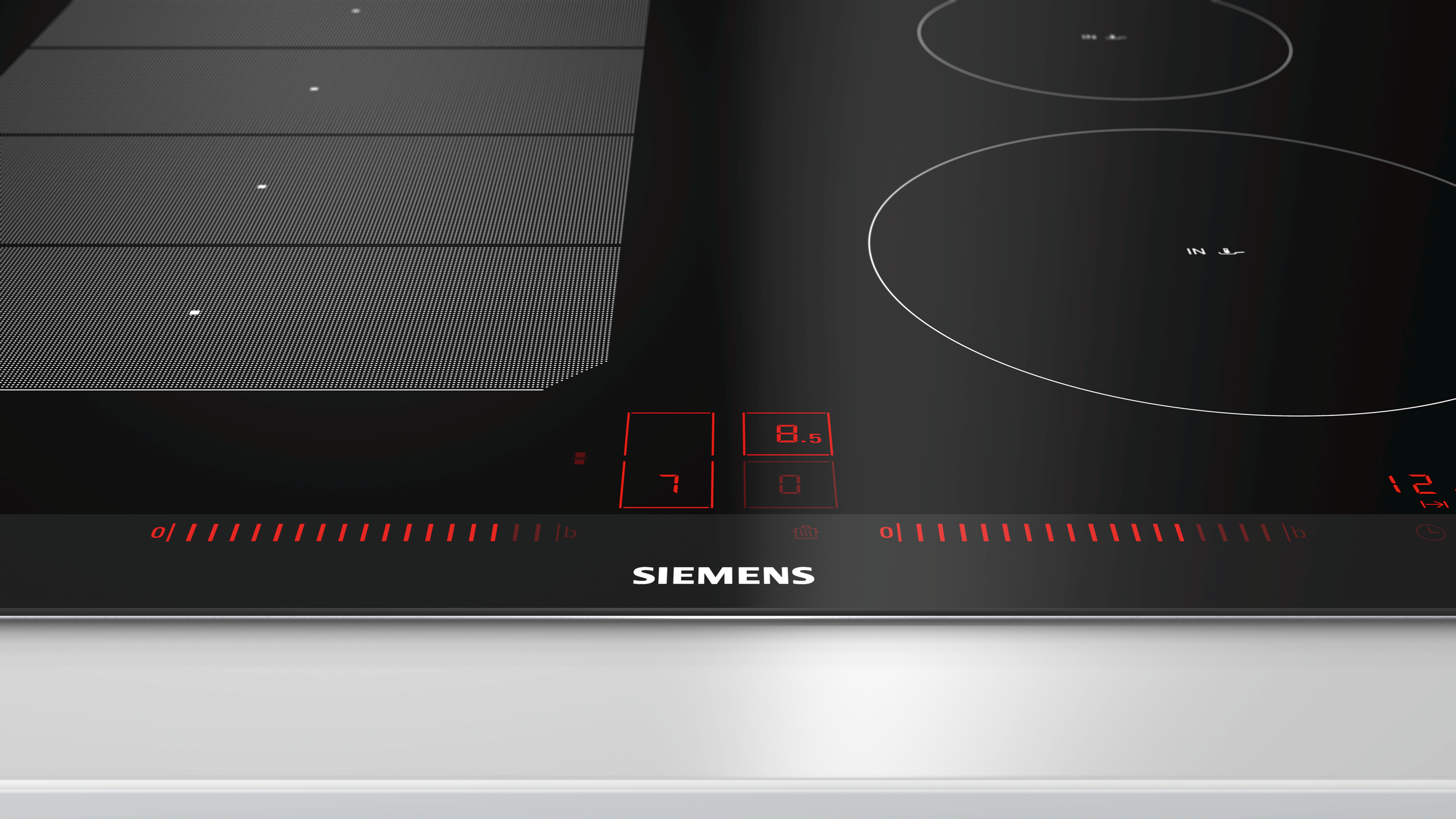 Table de cuisson en verre noir avec commandes tactiles et indicateurs rouges.