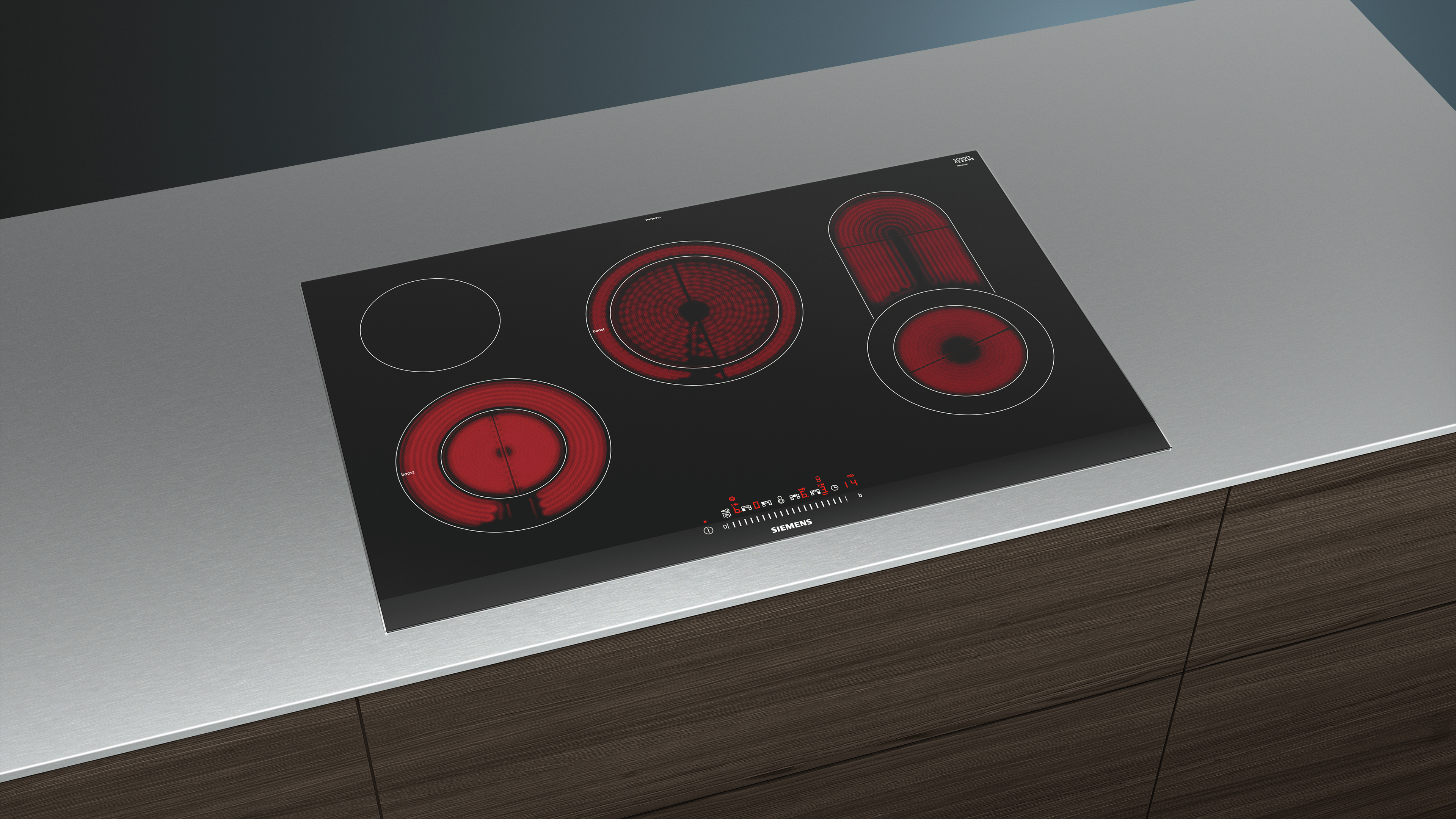 Table de cuisson électrique noire avec 5 foyers rouges éclairés, sur inox.