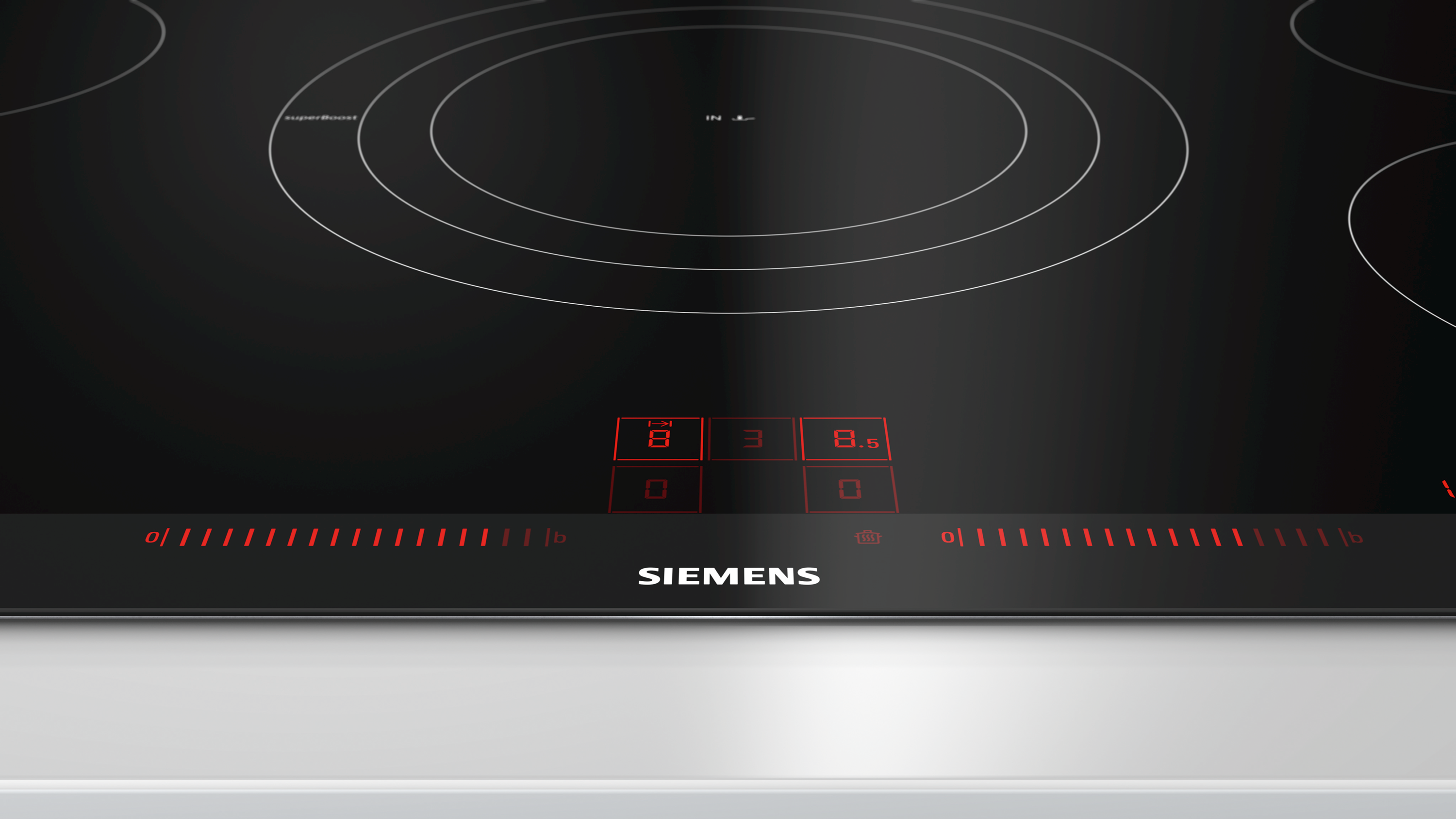 Gros plan sur une table de cuisson à induction Siemens noire avec commandes rouges éclairées et chiffres affichés.