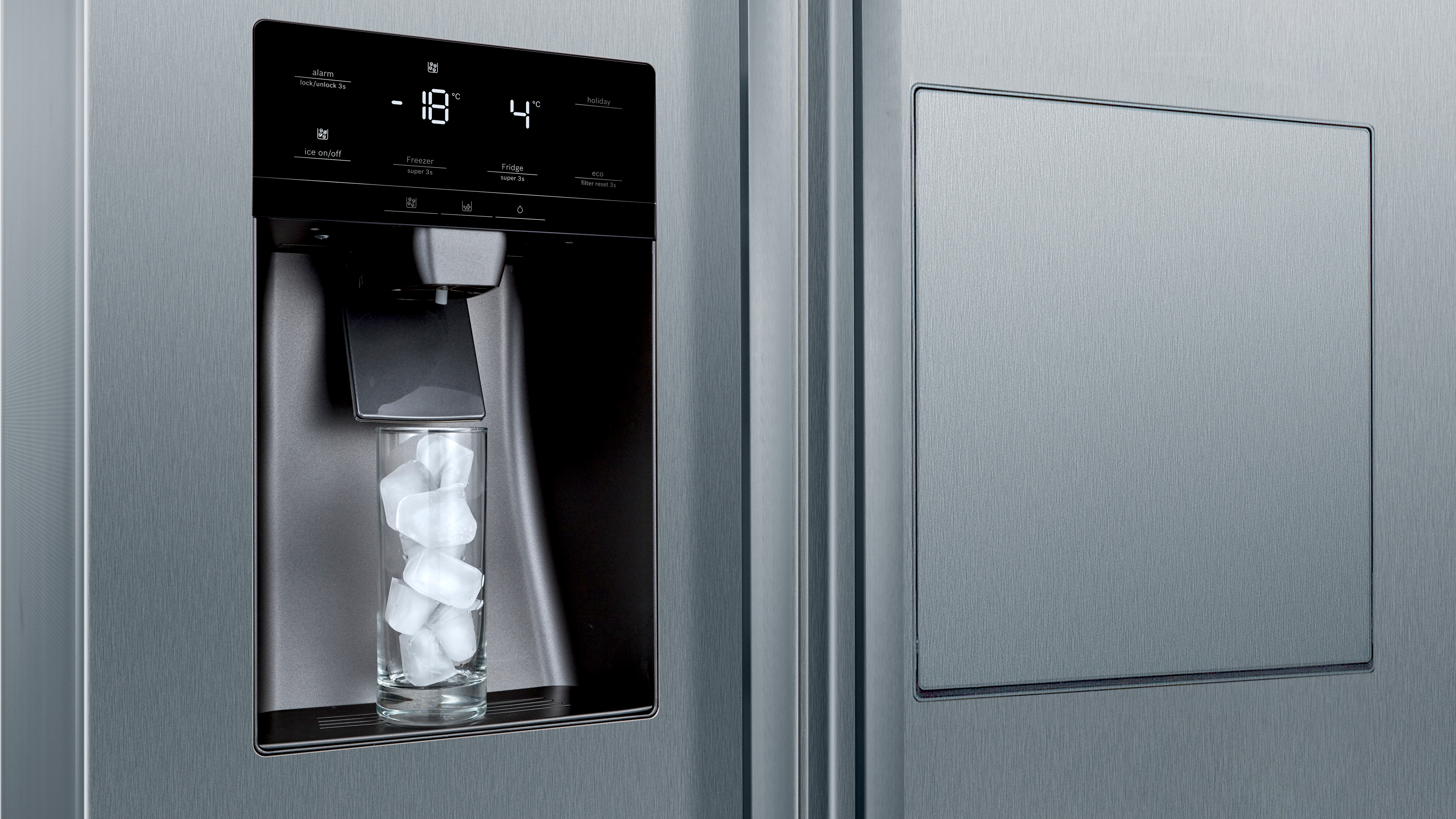 Ein Edelstahlkühlschrank mit Eis- und Wasserspender, der Eis in ein Glas abgibt.