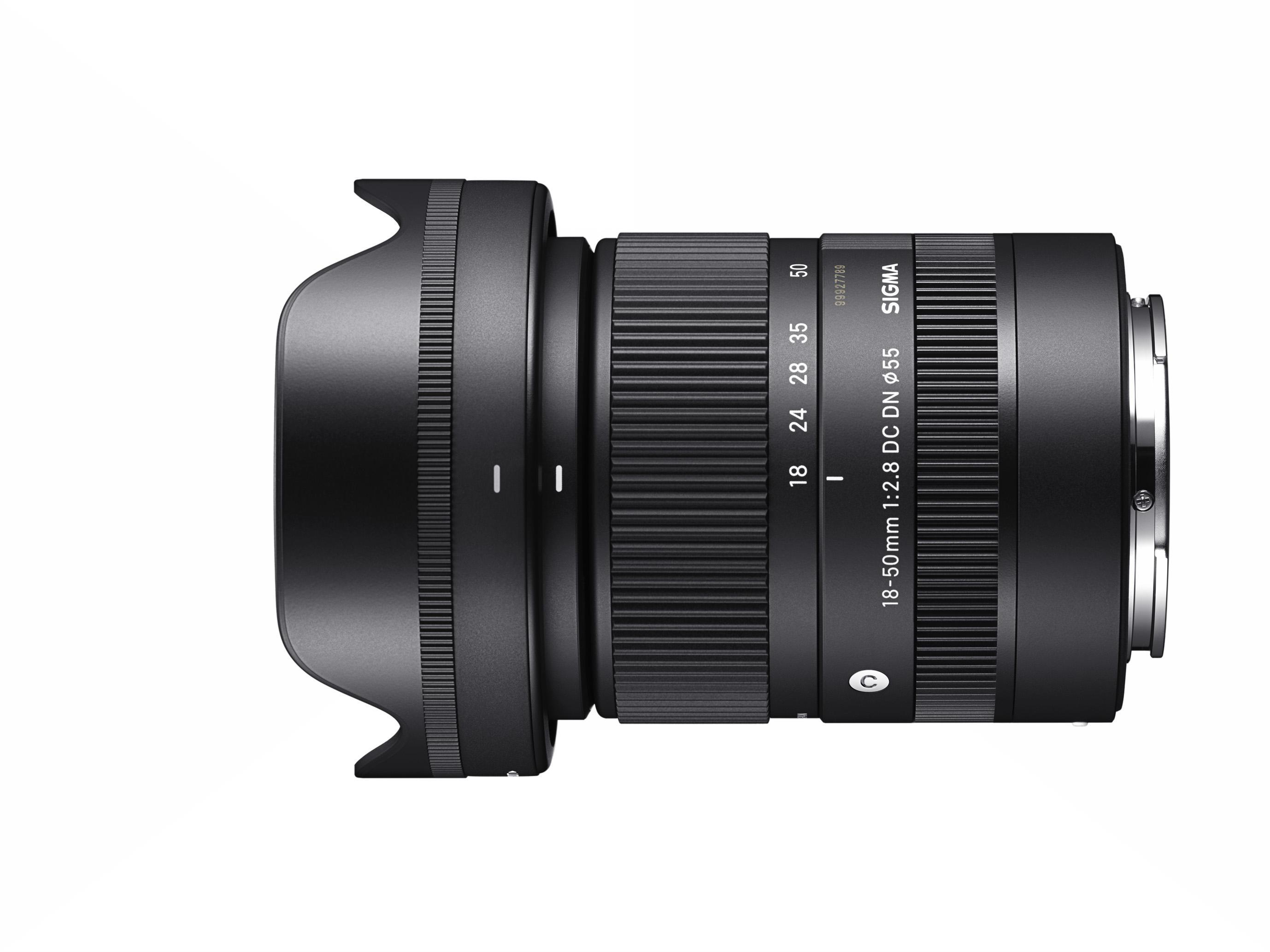 Ein Sigma 18-50mm Kameraobjektiv, schwarz, mit Gegenlichtblende, isoliert auf Weiß.