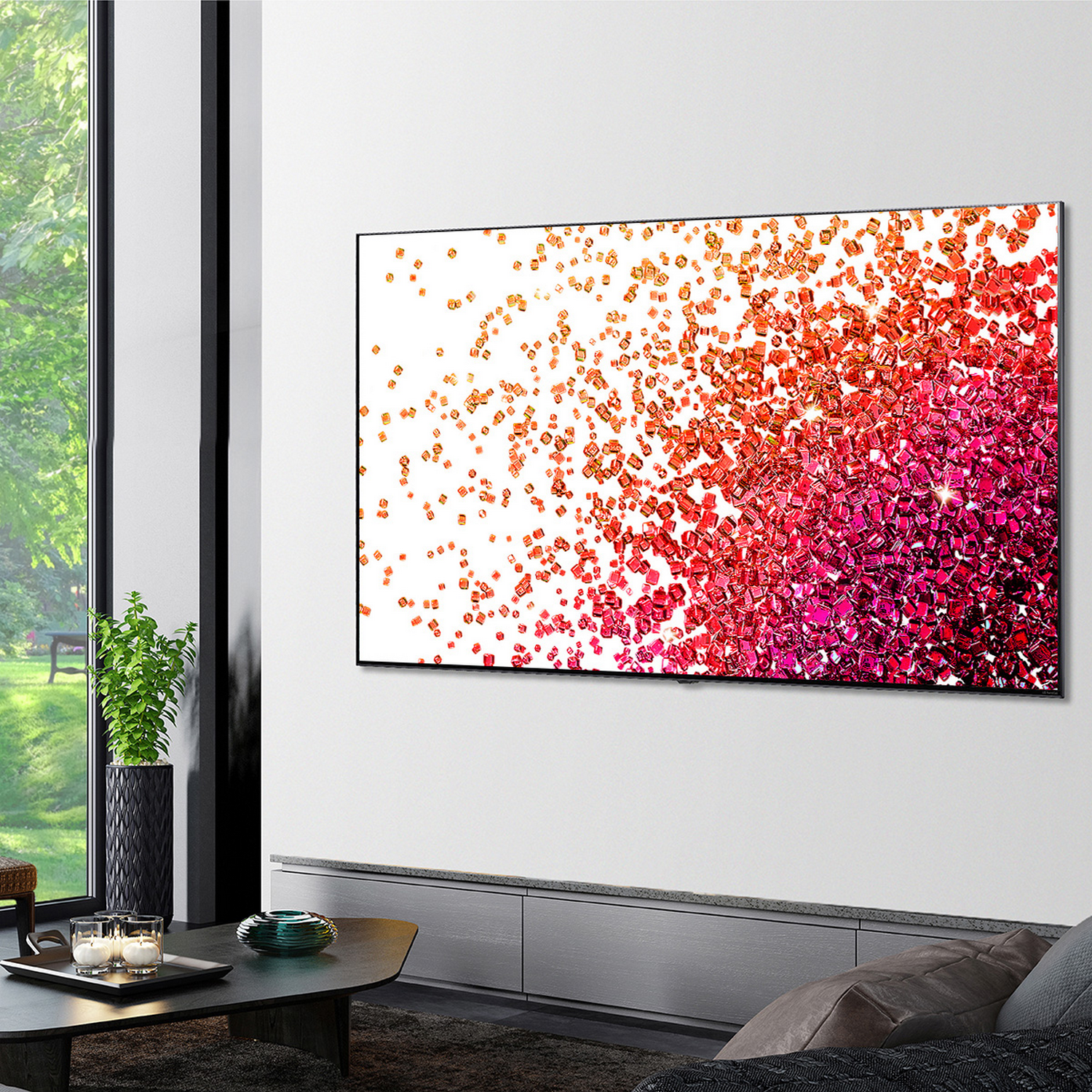 Pantalla de TV grande mostrando formas abstractas coloridas, montada en pared blanca.