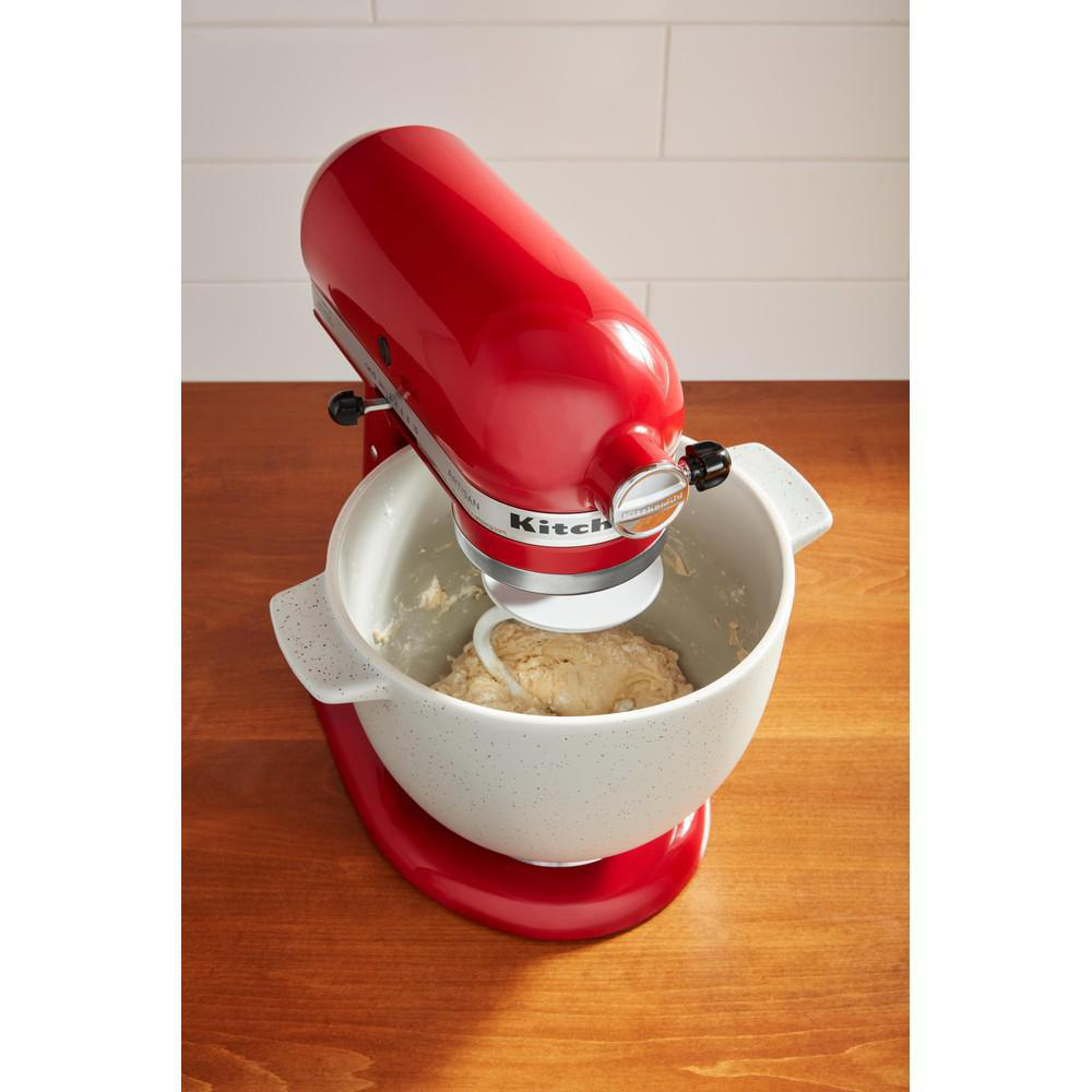 Roter KitchenAid-Mixer mit einer Rührschüssel mit Teig. Der Mixer steht auf Holz.