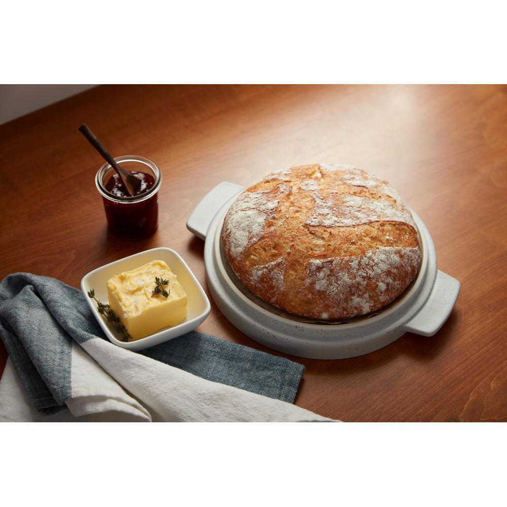 Brot in einer Backform, Butter und Marmelade auf Holz. Tisch mit Stoff.