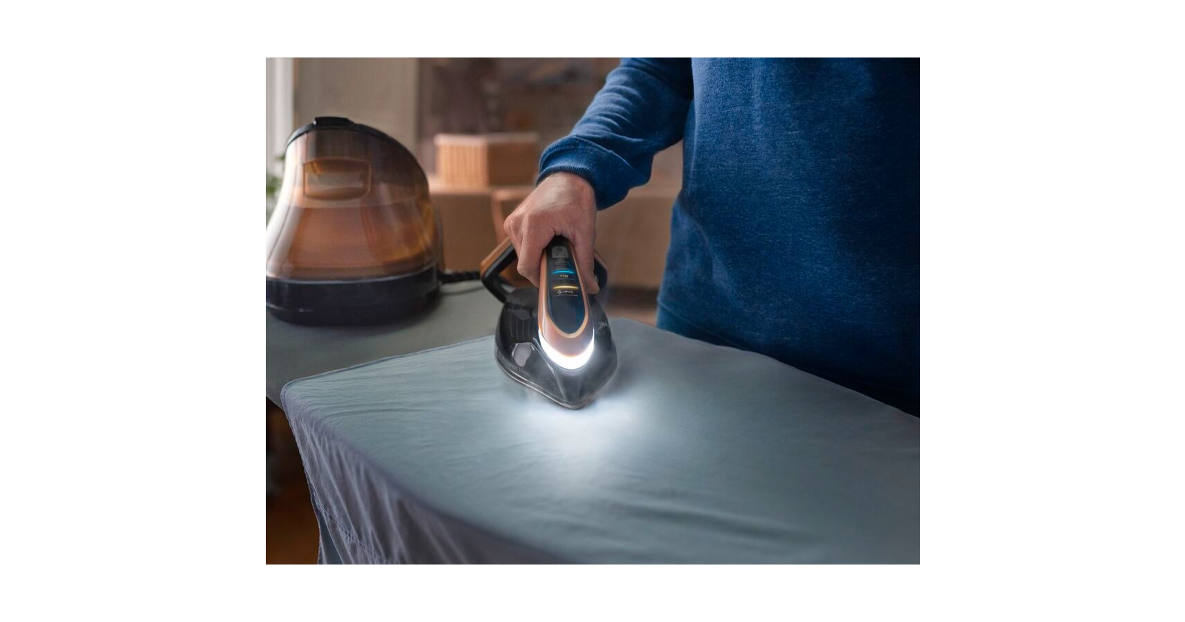 A person ironing a white shirt on an ironing board. The iron is glowing.