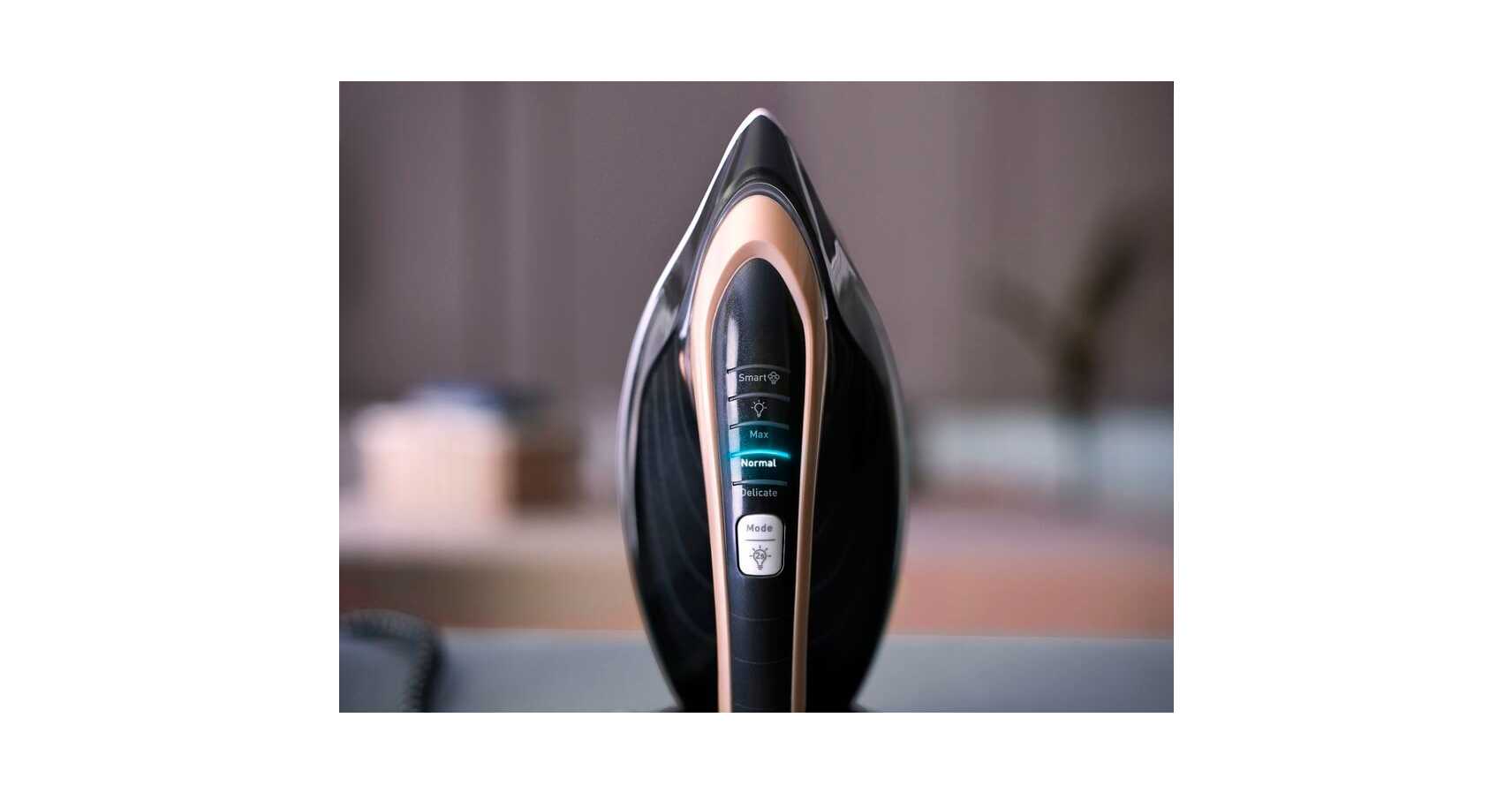 A black and bronze iron with a display showing settings, on a blurred background.