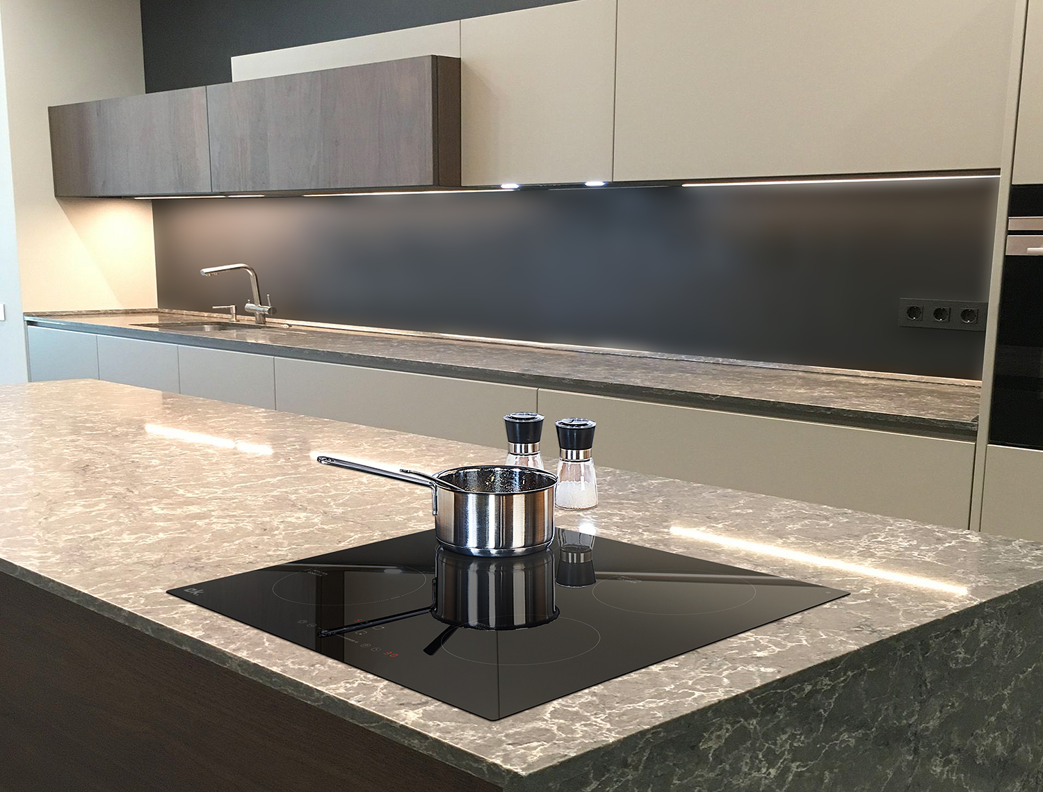 Modern kitchen with stainless steel pot on a black cooktop on a stone counter.