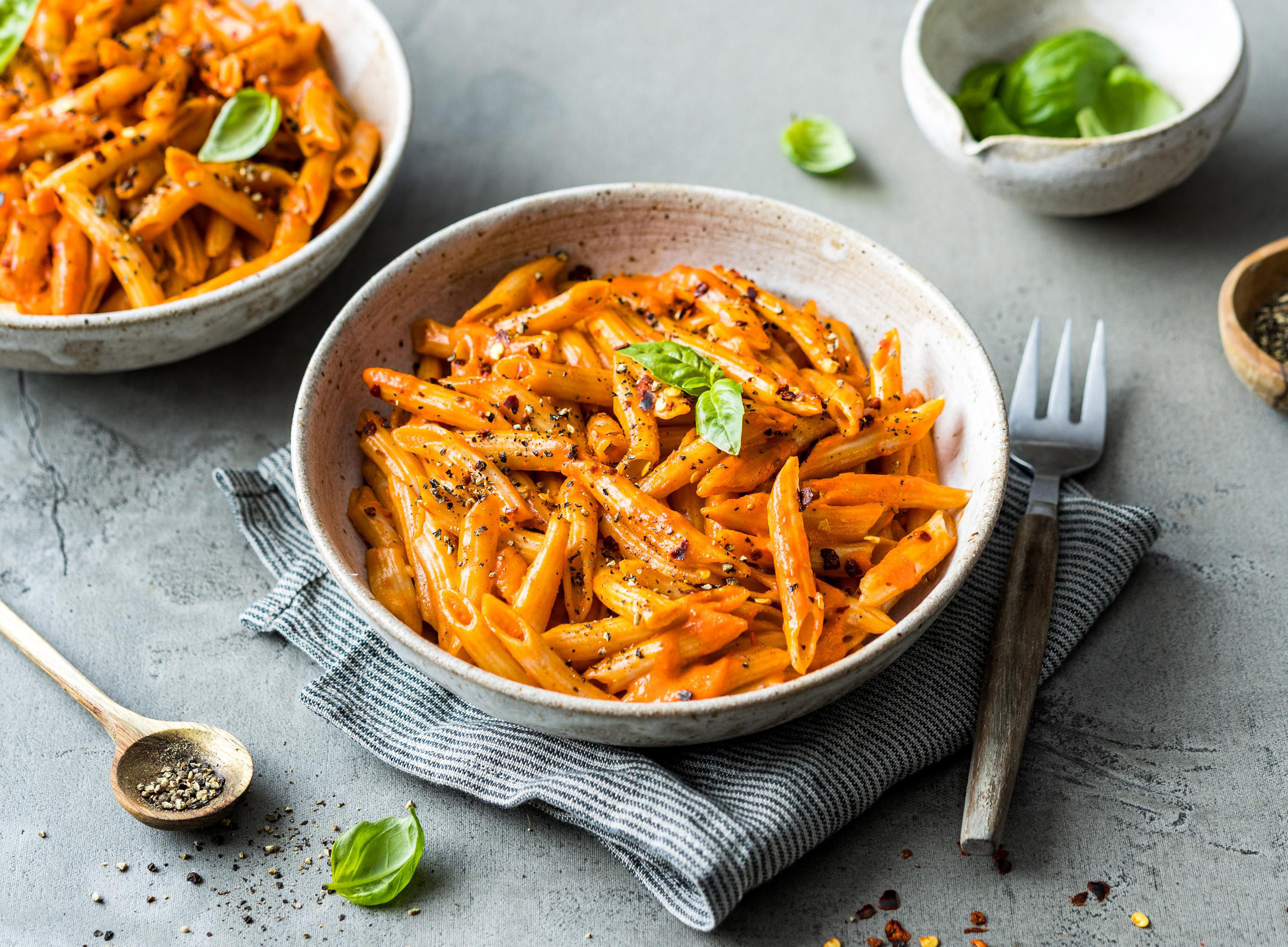 Zwei Schalen Pasta mit Tomatensauce. Die Schalen stehen auf einem grau-weiß gestreiften Tuch.