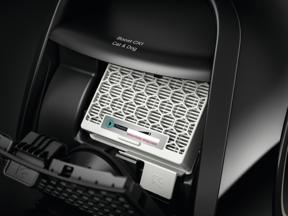 Close-up of a vacuum cleaner filter compartment. The filter is white, and a QR code sticker is visible.