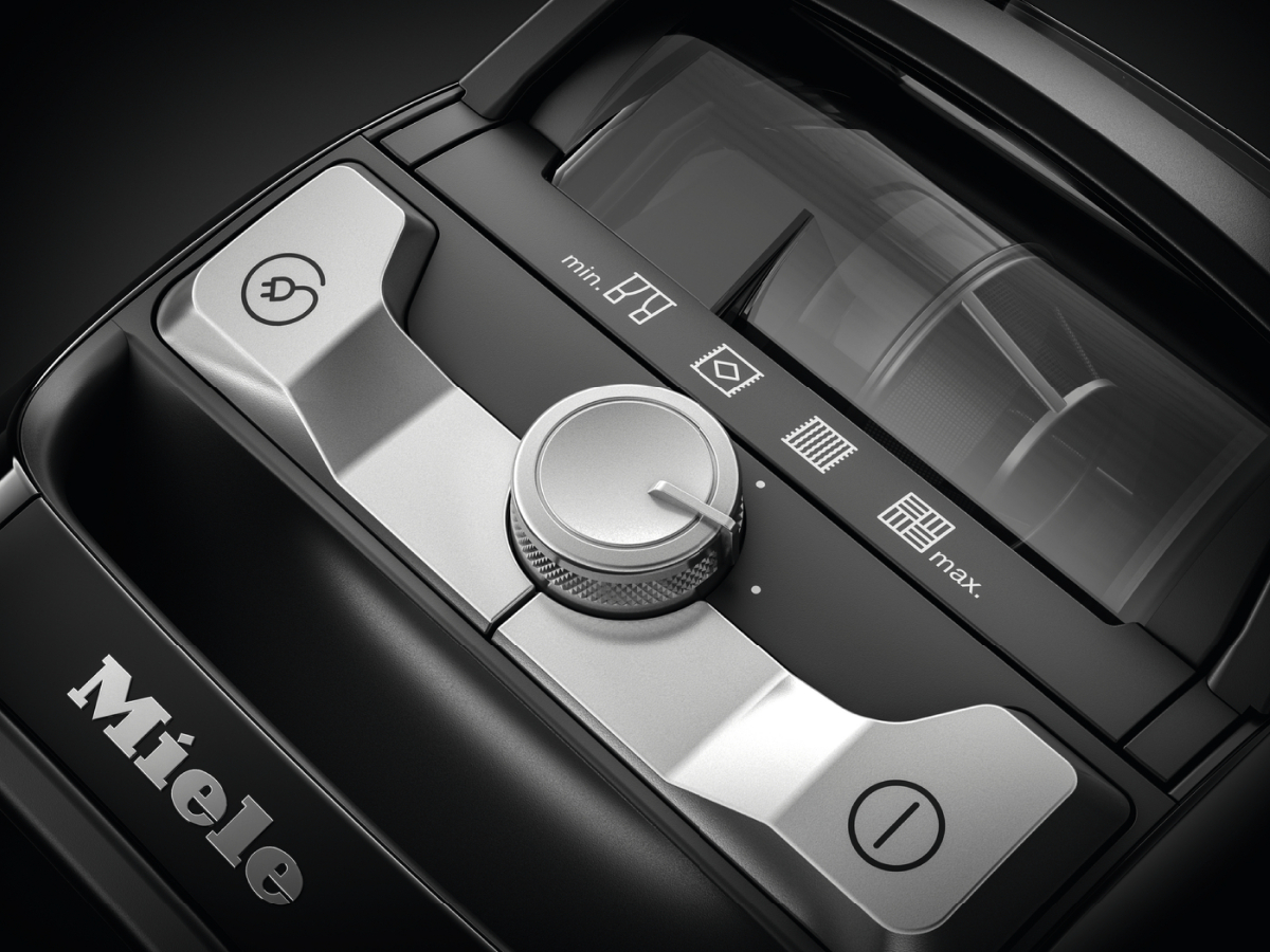 Close-up of vacuum cleaner controls, black and silver, with 'Miele' logo.
