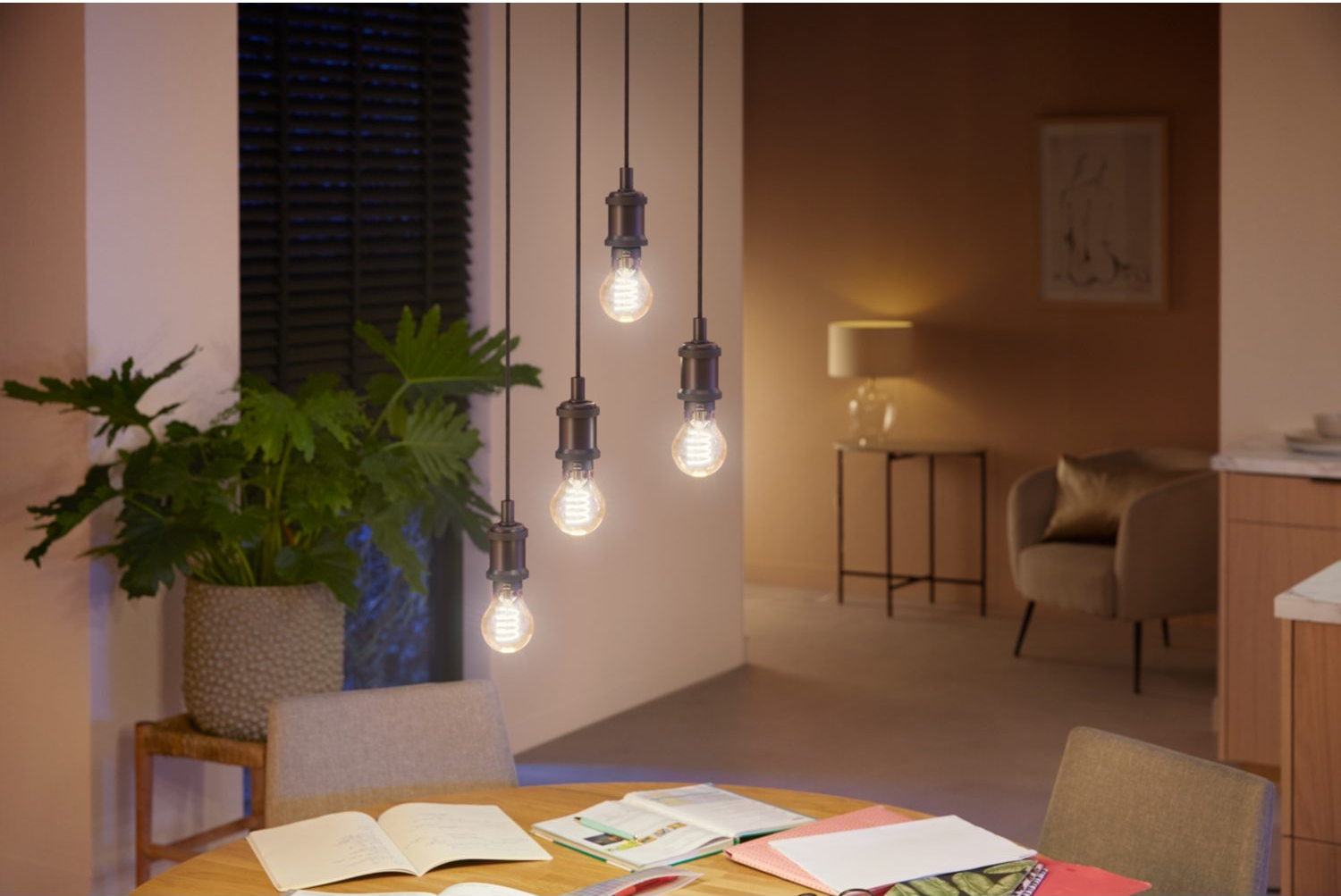 Scène intérieure avec suspensions, table à manger et grande plante en pot.
