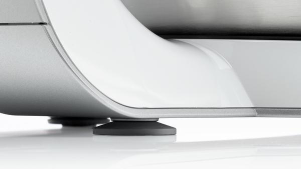 Nahaufnahme des Sockels eines weißen Geräts mit kleinen, dunkelgrauen Füßen.