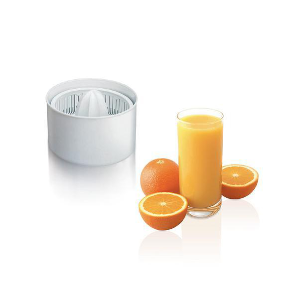 Entsafter und Glas Saft. Orangen, halbiert, liegen neben Glas und Entsafter auf weißer Oberfläche.