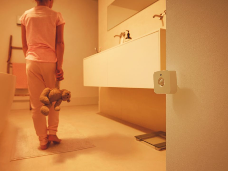 Un enfant dans une salle de bain avec un interrupteur de lumière intelligent sur le mur.