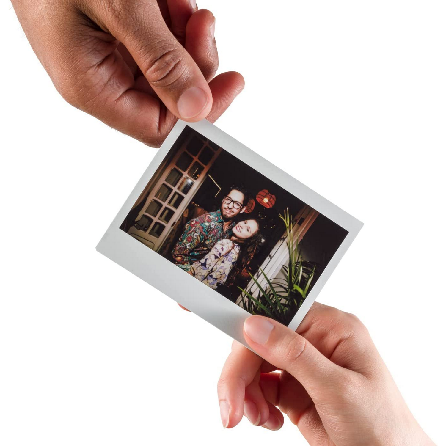 Manos sosteniendo una foto polaroid de una pareja, interior, caras felices.