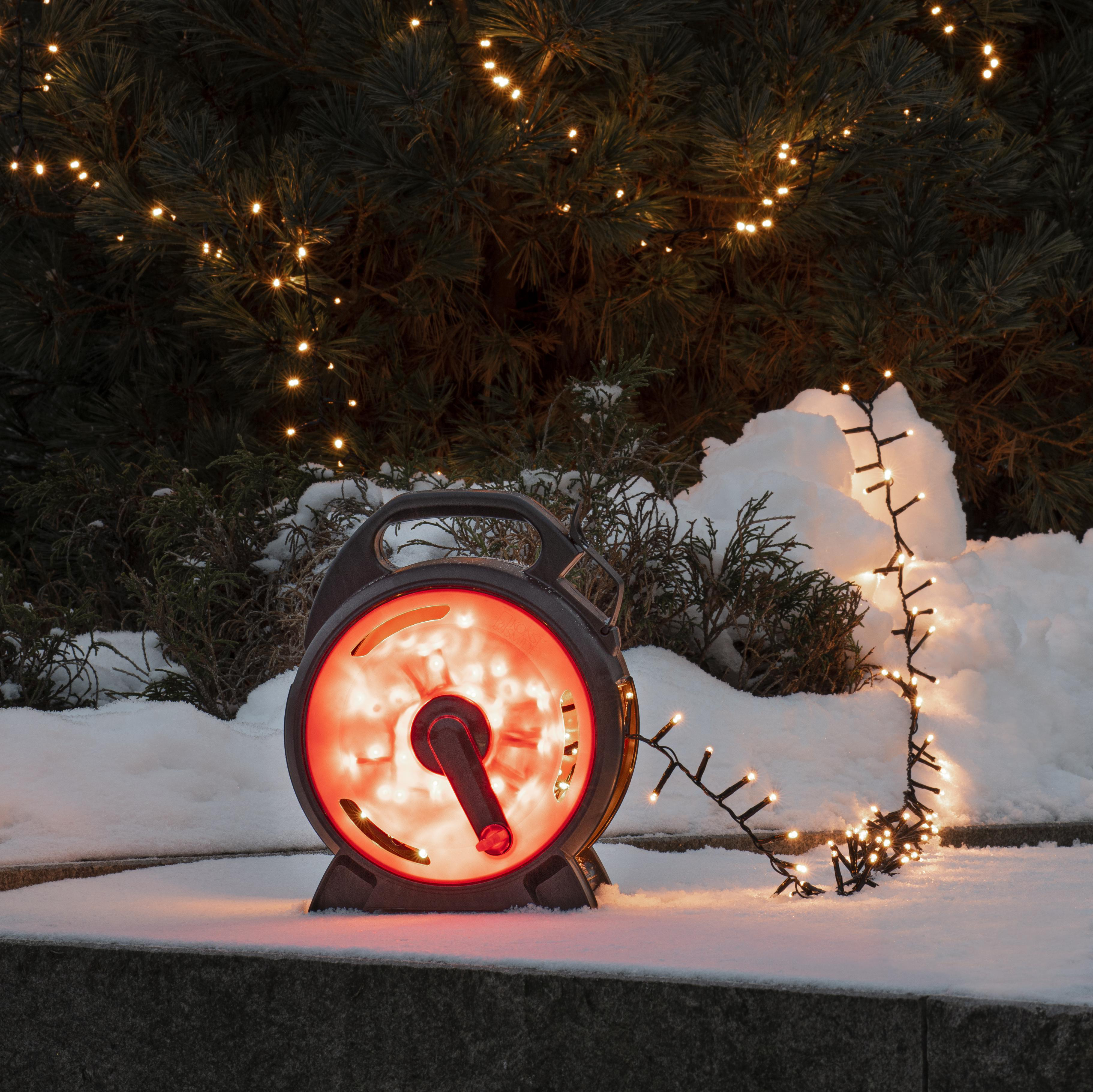 Außenszene mit Weihnachtsbeleuchtung. Eine schwarze, rot beleuchtete Lichtrolle und Schnee sind sichtbar.