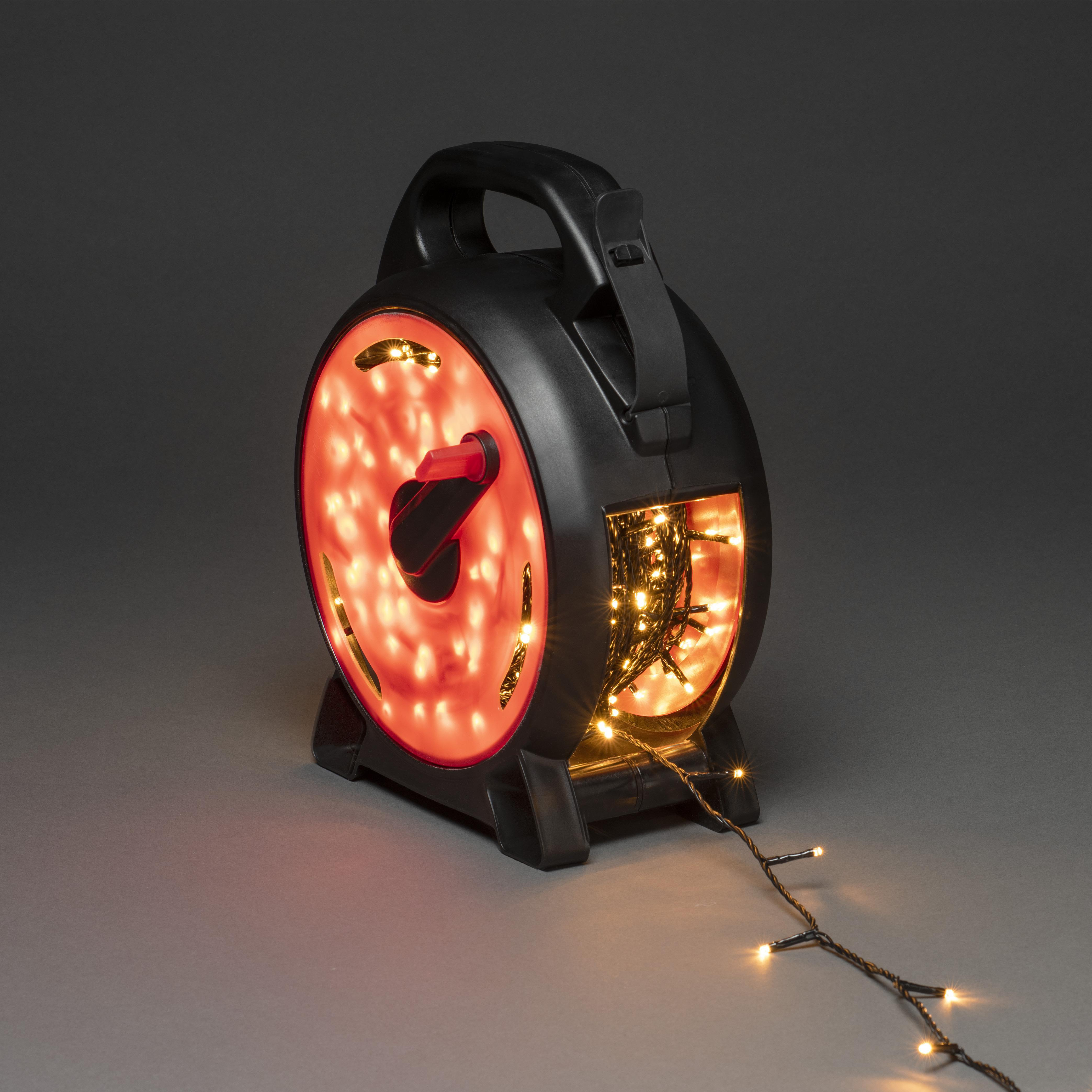 Schwarze Kabeltrommel mit roten Lichtern und einer Lichterkette. Griff oben.