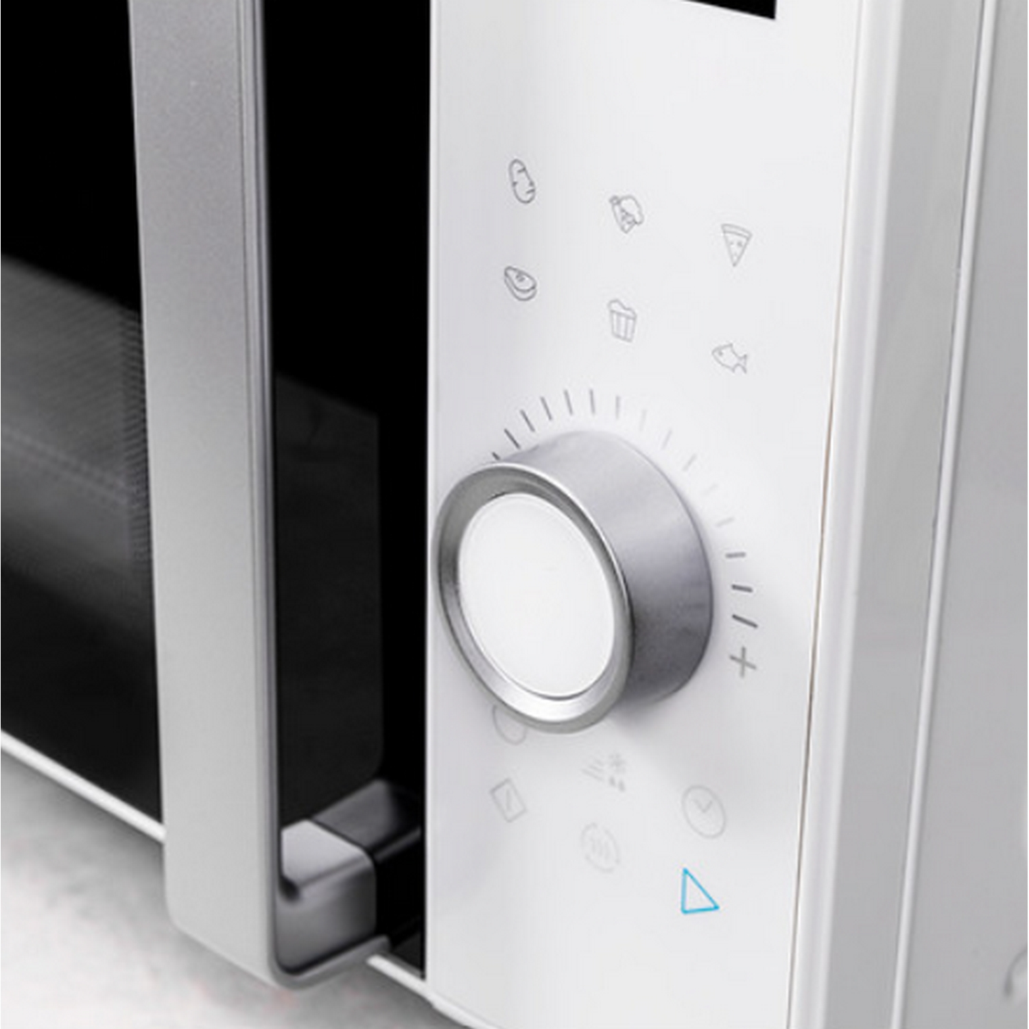 Primer plano de un microondas blanco con dial de control e iconos.