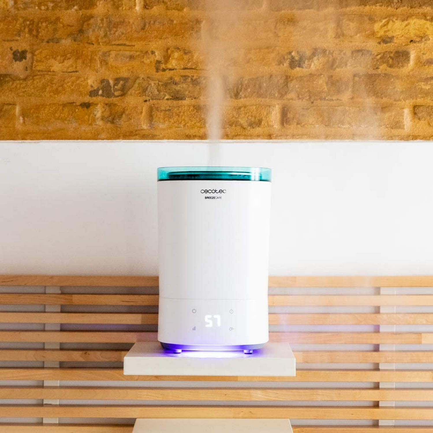 Un humidificador blanco con tapa azul emite vapor. Está sobre un estante.