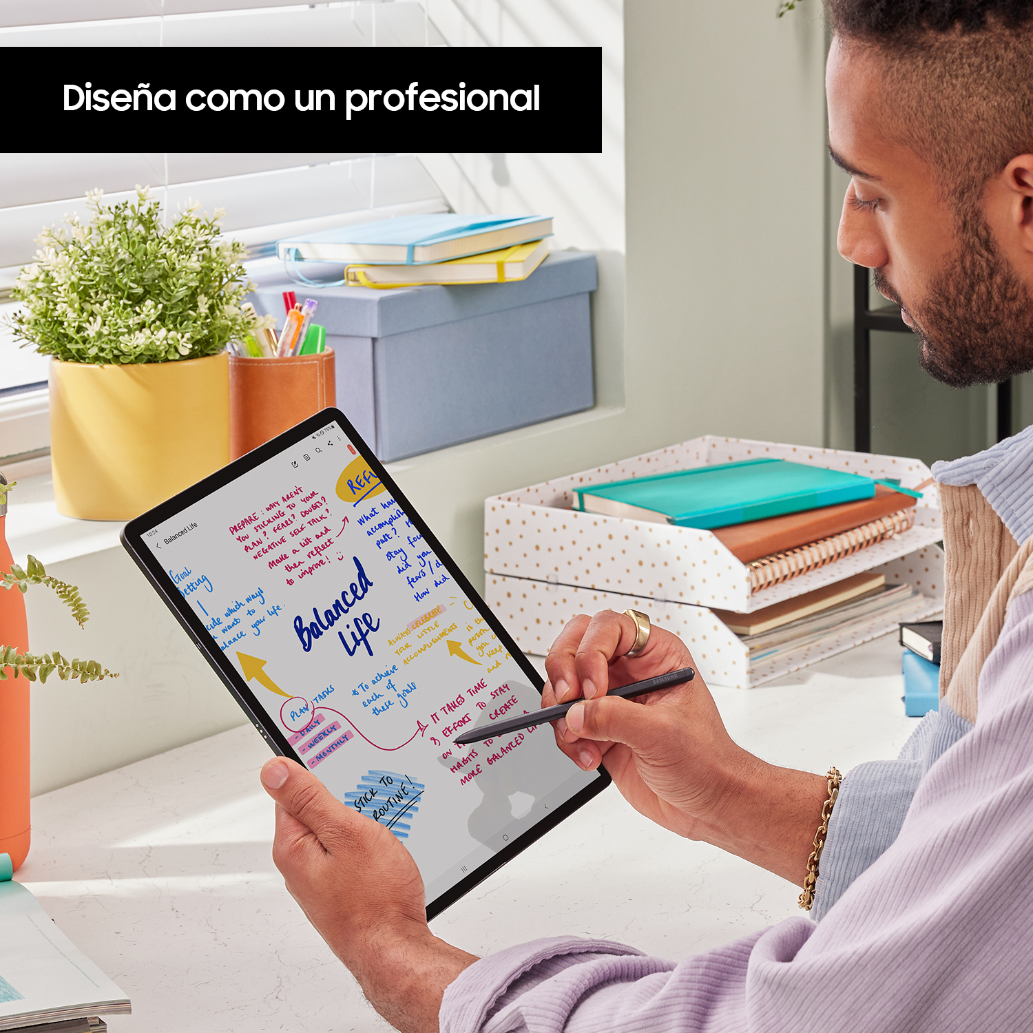 Un hombre escribiendo en una tableta con un bolígrafo, con un cuaderno y organizadores de escritorio en el fondo.