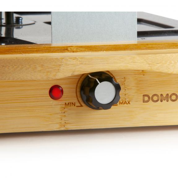 Close-up van een bamboe-stijl kookplaat bedieningspaneel met rood licht en een knop.