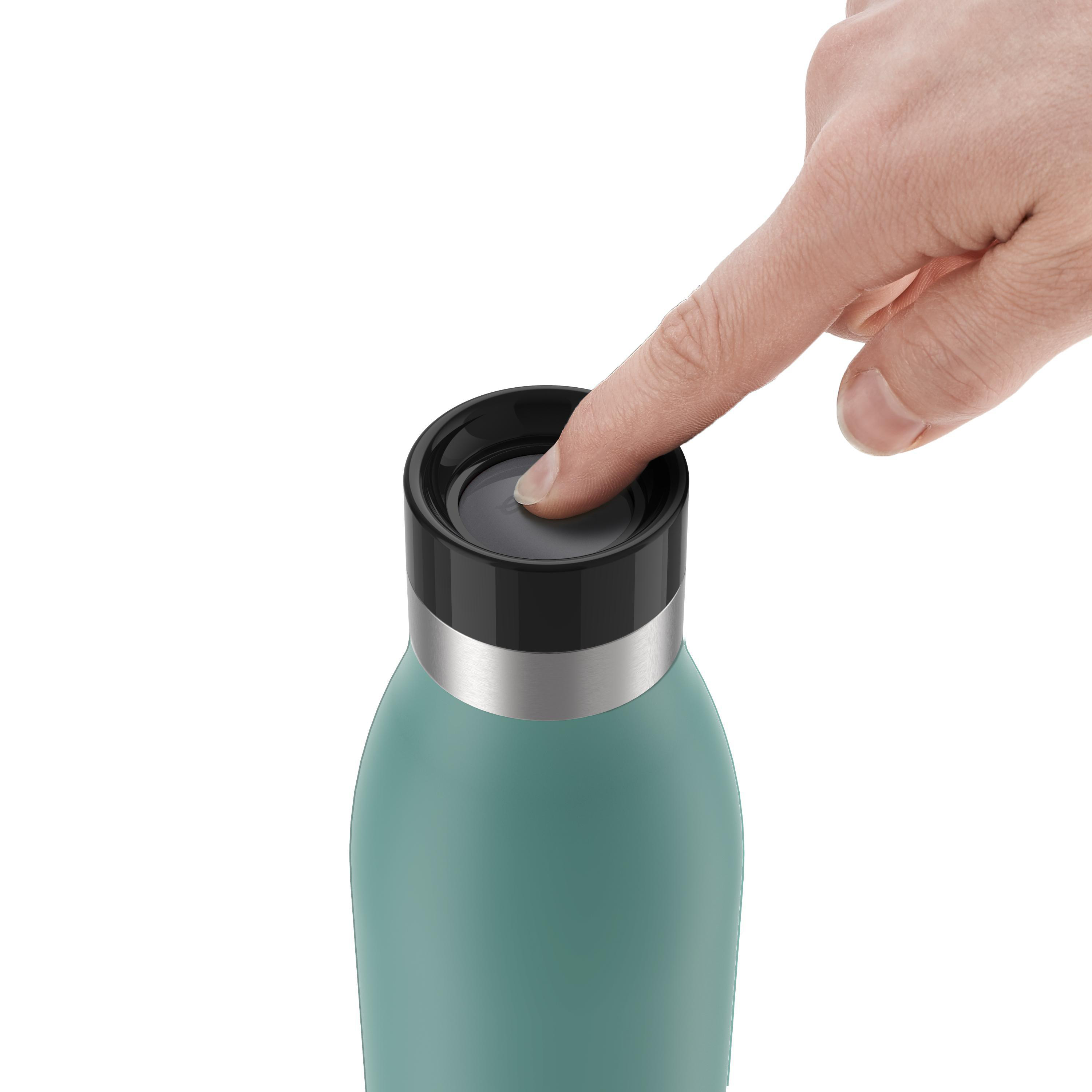 Hand drückt auf den Deckel einer teal-farbenen Flasche. Silbernes Band oben. Weißer Hintergrund.
