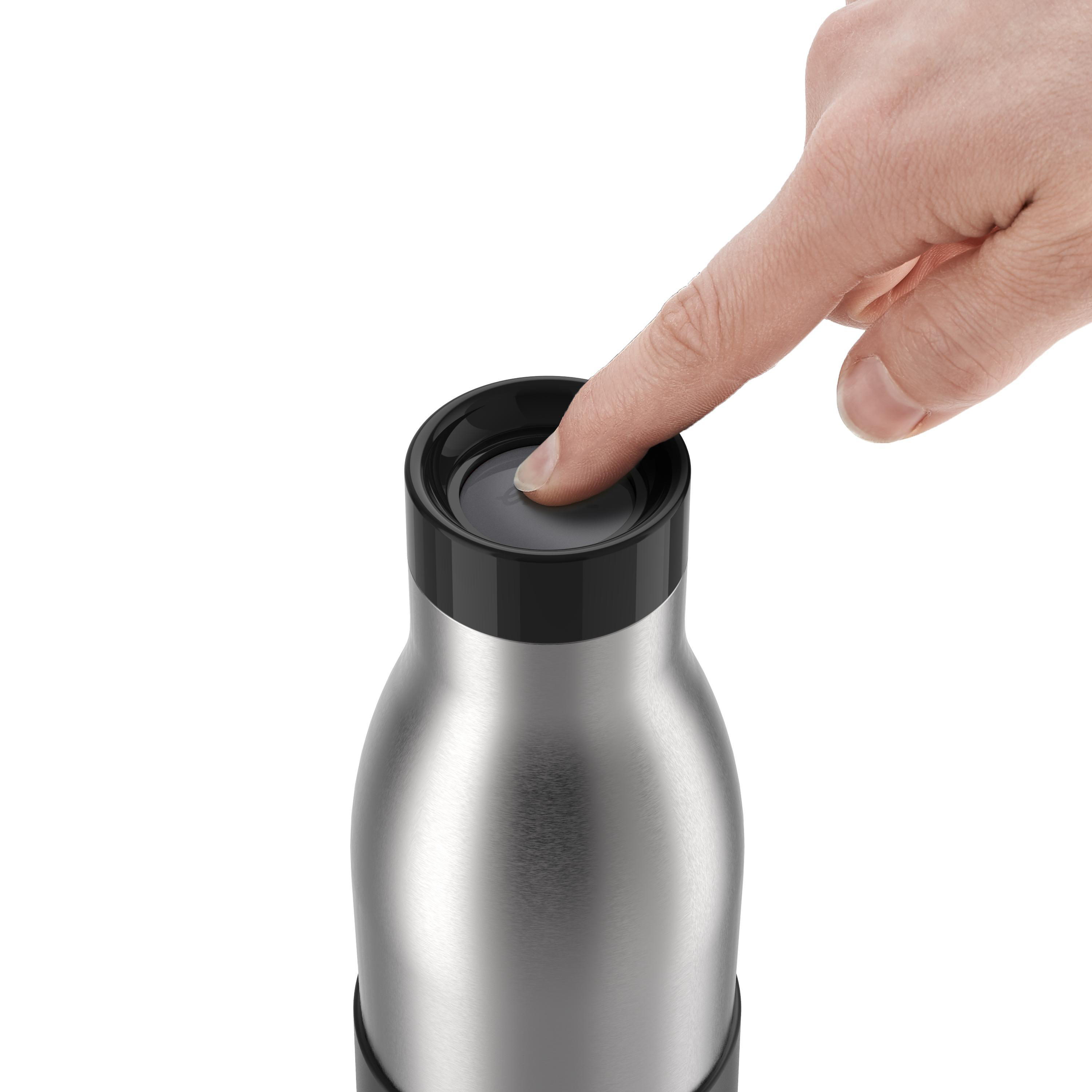 Hand drückt auf die obere Taste einer silbernen Wasserflasche mit schwarzem Boden.