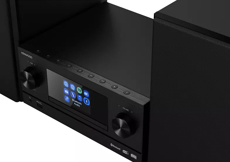 Een zwart Kenwood stereosysteem met een scherm en knoppen, geplaatst tussen twee luidsprekers.