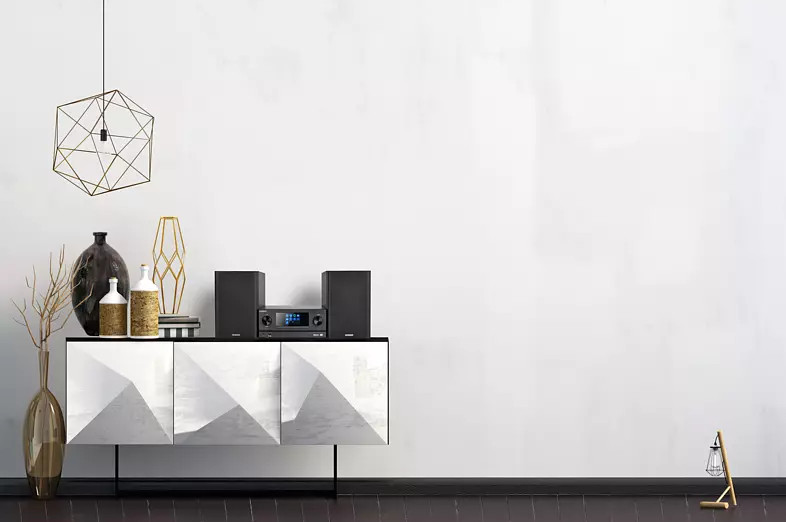 Een moderne woonkamer met een witte muur. Een witte kast met kunst en luidsprekers staat in het midden.